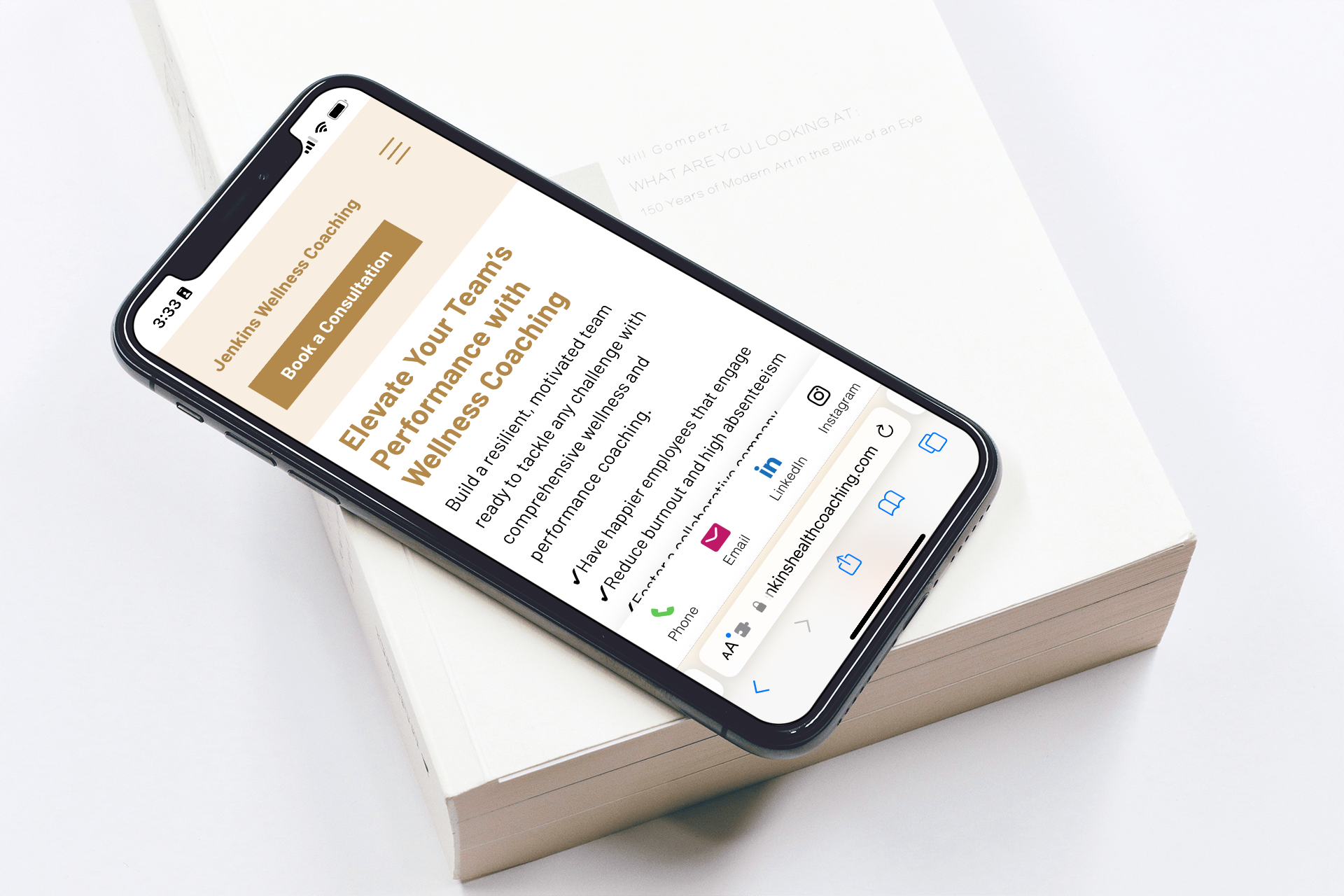 Smartphone displaying Jenkins Wellness Coaching website page on performance coaching, resting on an open book.