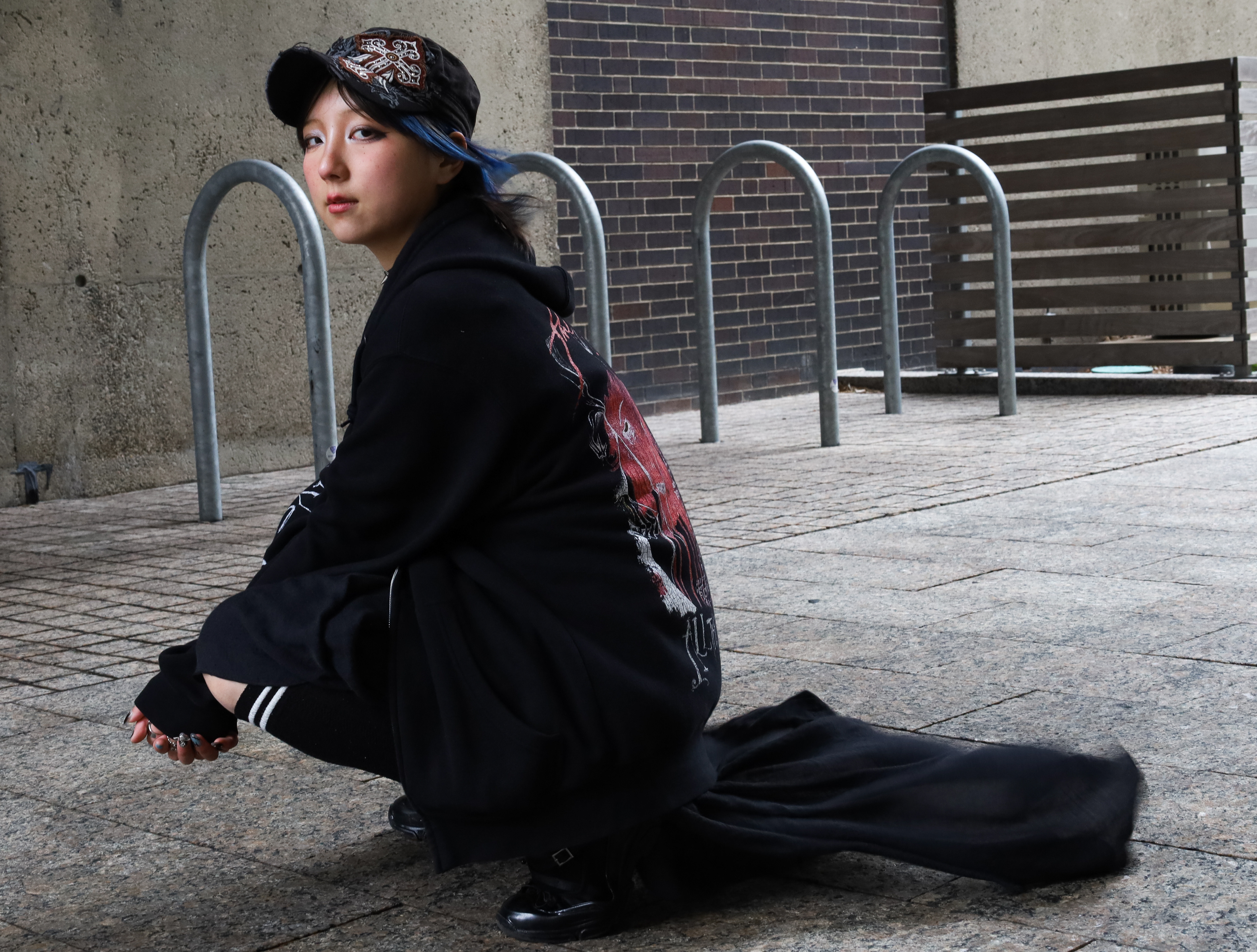 Sawyer Yoh squatting outside of Boston University's School of Law; March 30th, 2025.