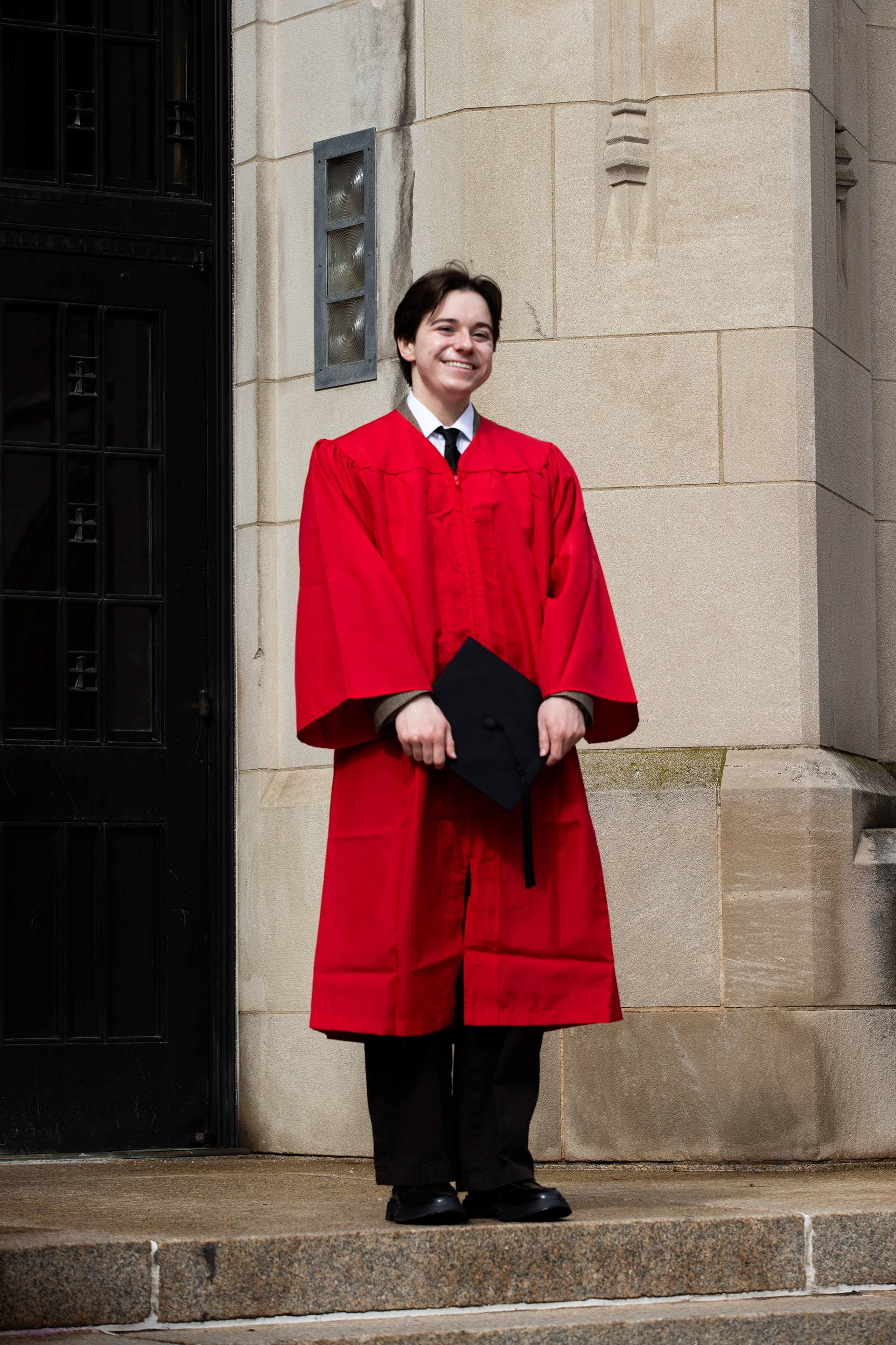 Kenny Daniels wields his graduation cap, standing next to the side entrance of Boston University's School of Theology where Daniels has spent much of his undergraduate career studying and taking classes at; March 8th, 2026.