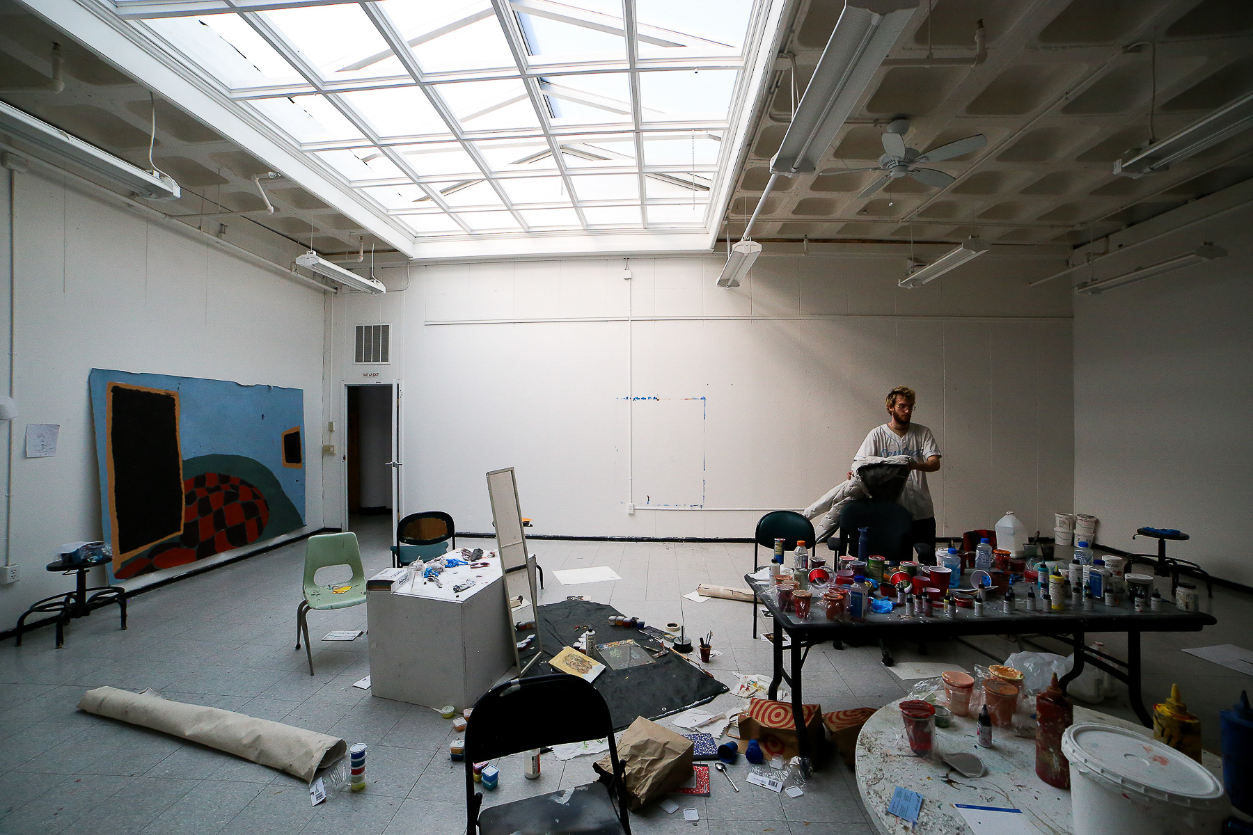 Stephen Barratt begins to set his coat on top of a distressed chair. In the wide photo, shows one of three spaces in which Barratt stores his art materials; February 28th, 2025.