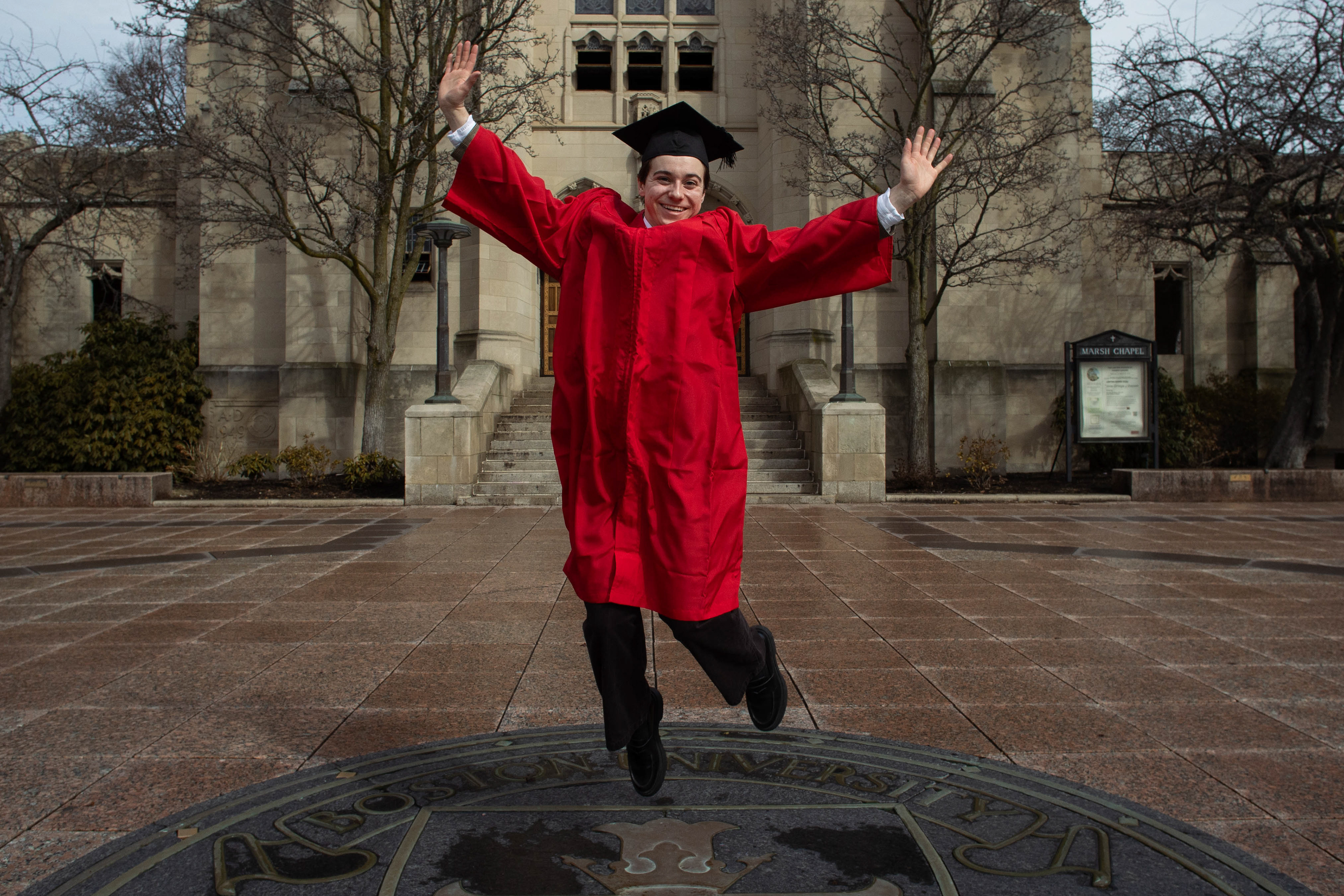 Kenny Daniels jumps with joy on top of the infamous Boston University crest, wearing his cap and gown; March 8th, 2026.