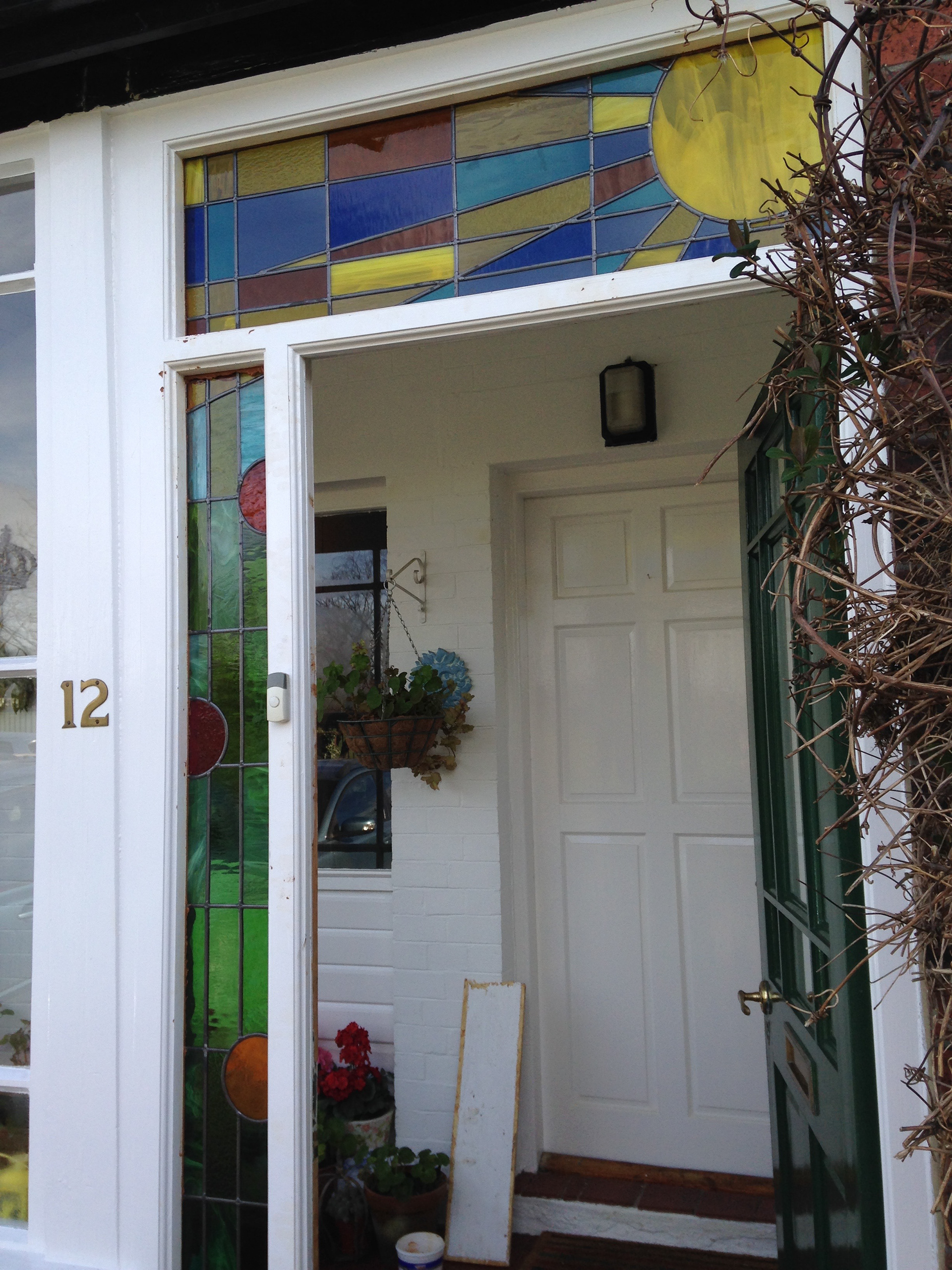 Stained glass in Headingley Leeds. Original Clarice Cliff themed design in art glass. Sunshine, sunbeams with abstract nasturtiums for external wooden door frame - seen from the outside