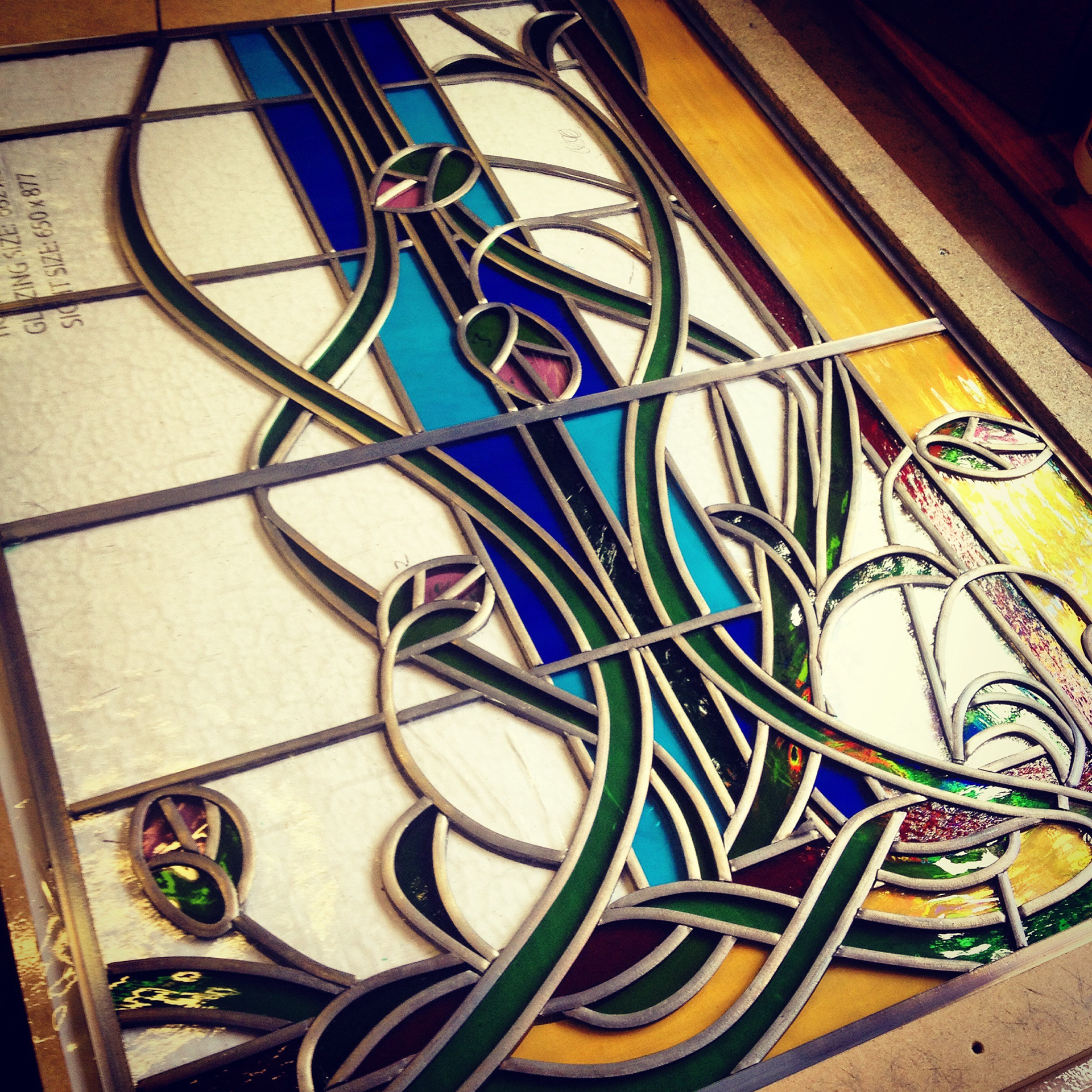 Traditional Stained glass leaded light original Art Nouveau theme by Zoe Eady of The Glass Garden. Compound design - Lotus flowers with buds entwining between the panels. Close up of the bottom panel under construction