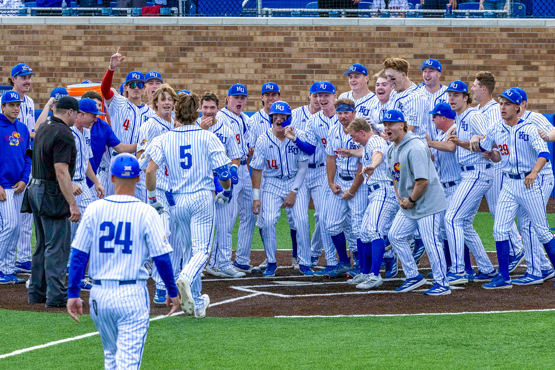 As KU shortstop Sawyer Smith (5) approaches home plate after hitting a three-run walk-off home run against Oklahoma State, his teammates wait around the plate to celebrate on Saturday, March 29, 2025, at Hoglund Ballpark in Lawrence, Kan.