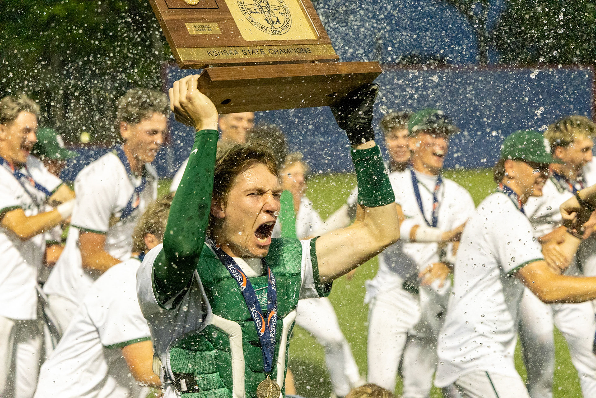 Free State senior Andrew Zimmerschied is blasted with water as he hoists the state championship trophy on Friday, May 30, 2025, at Hoglund Ballpark in Lawrence.
