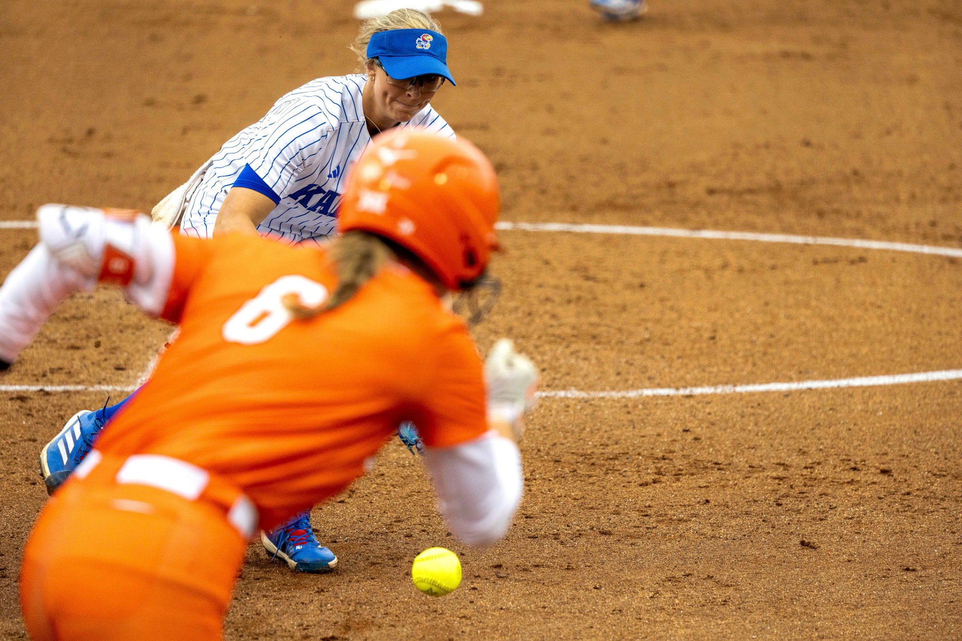 KU senior Katie Brooks fields a short chopper as Oklahoma State red shirt junior Audrey Schneidmiller races down the line on Sunday, April 27, 2025, at Arrocha Ballpark in Lawrence, Kan.