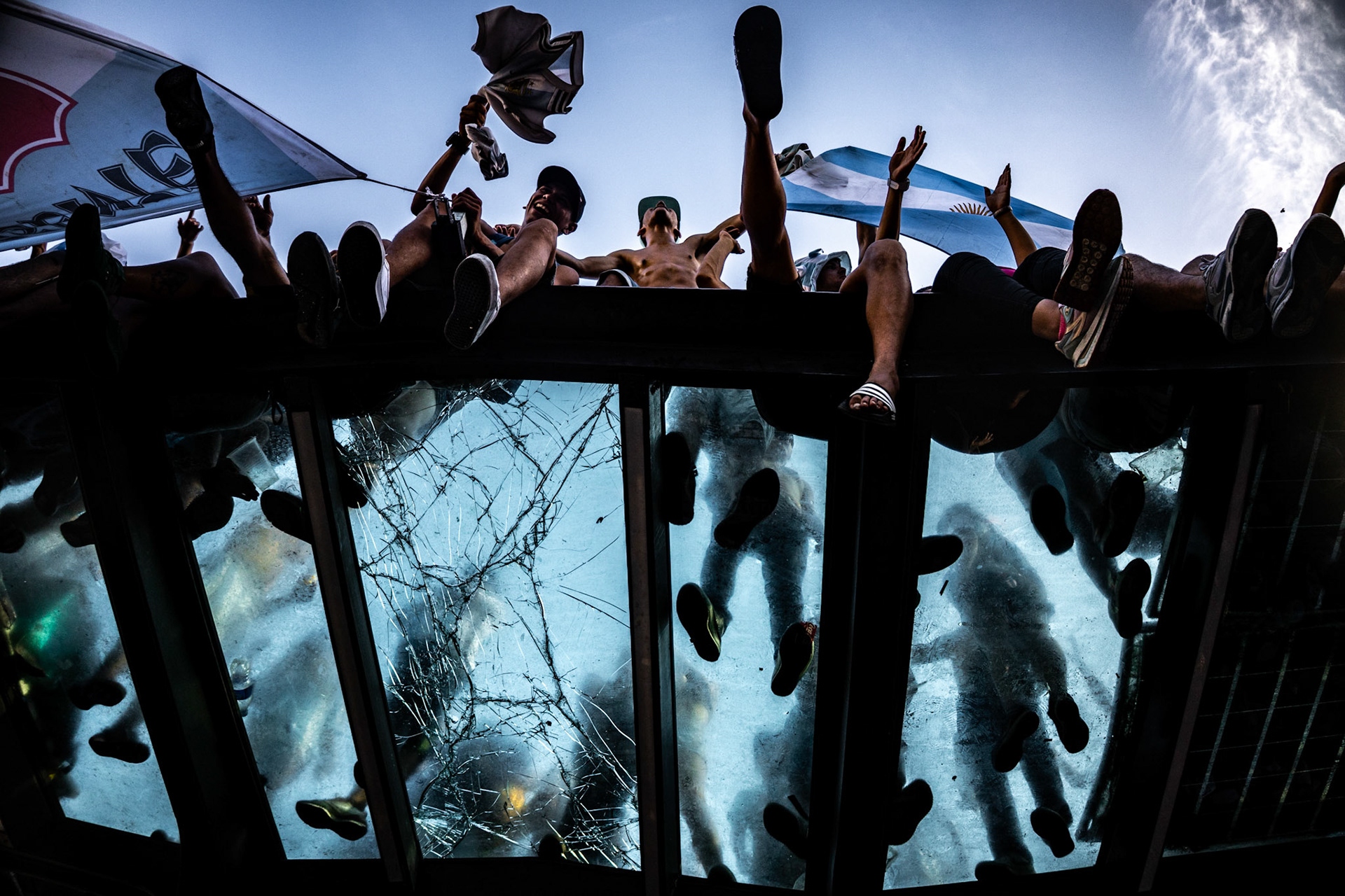 People stand on top of a bus stop shelter during celebrations for Argentina’s FIFA World Cup Qatar 2022 victory | Buenos Aires, 2022.