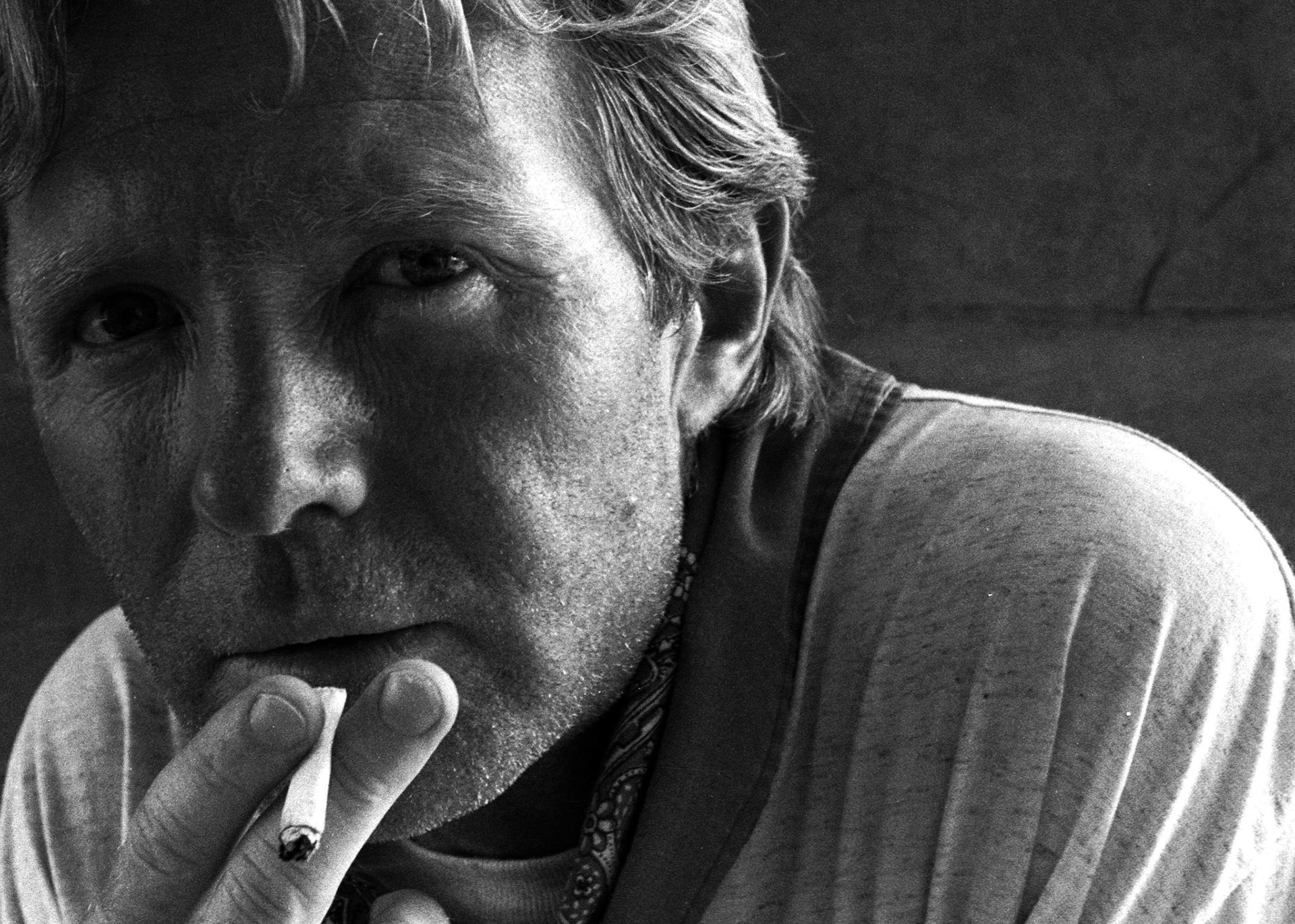Stock image of a man smoking in the jungle and looking very unwell and haunted