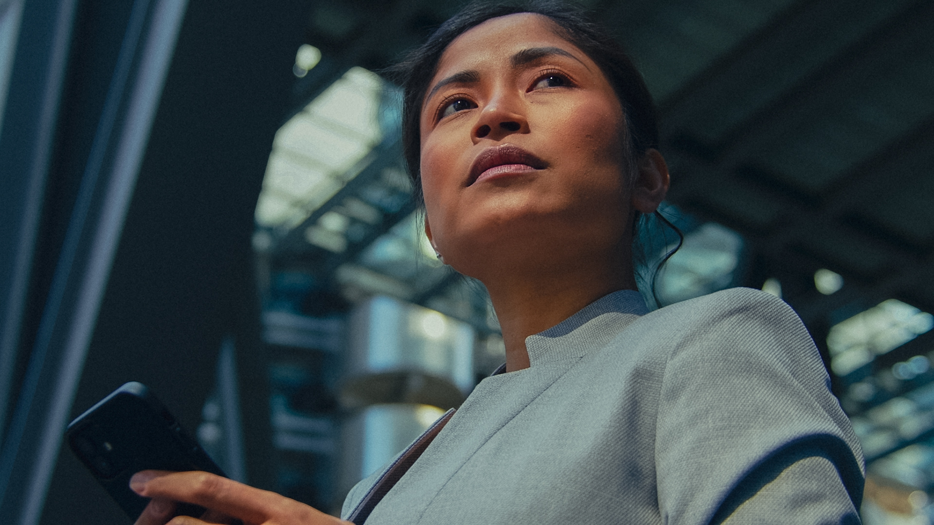 Businesswoman using smartphone in front of modern architecture — professional video production for Kent businesses and brands