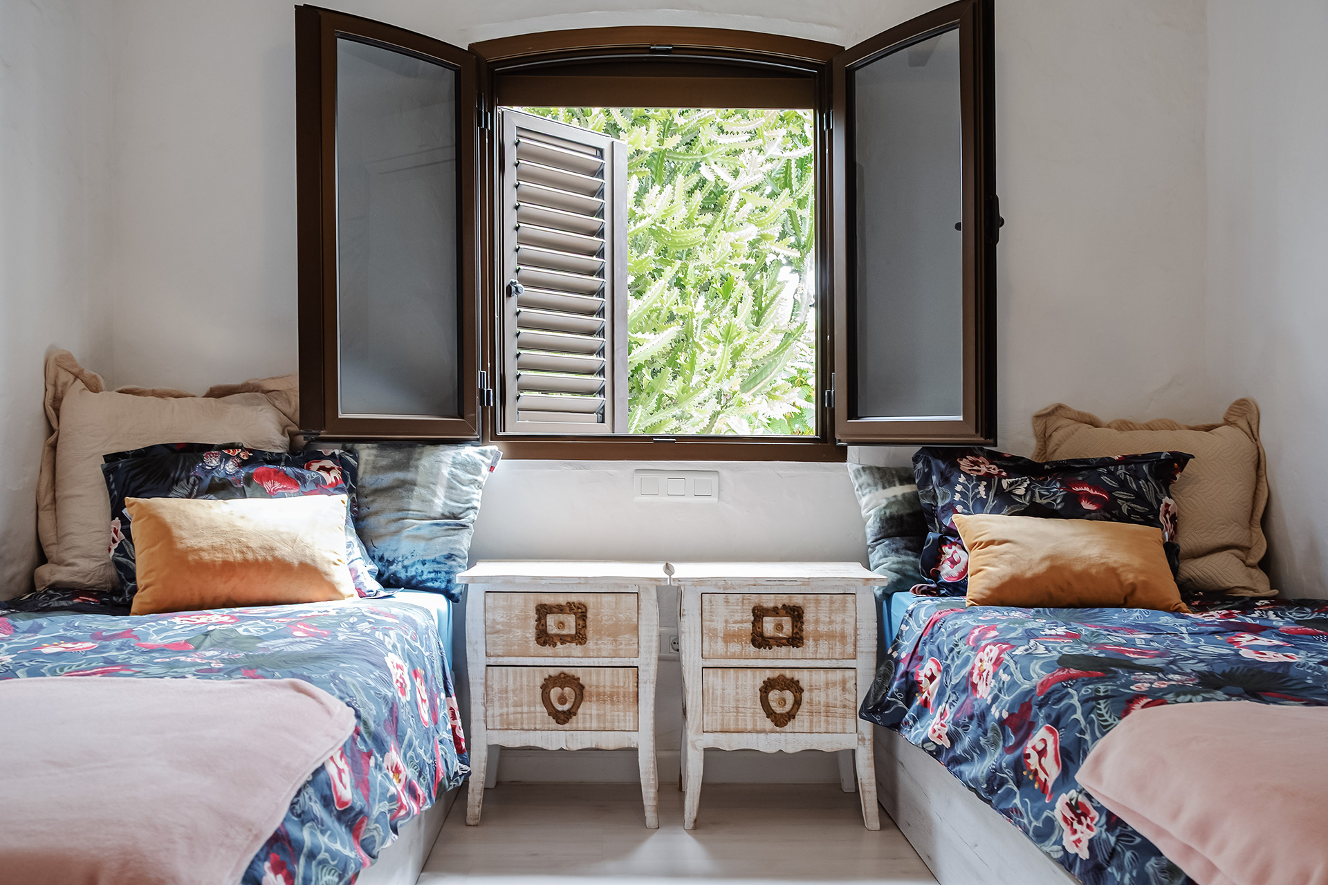 Dormitorio doble con ventana abierta y vistas a jardin de cactus en apartamento turistico en Maspalomas