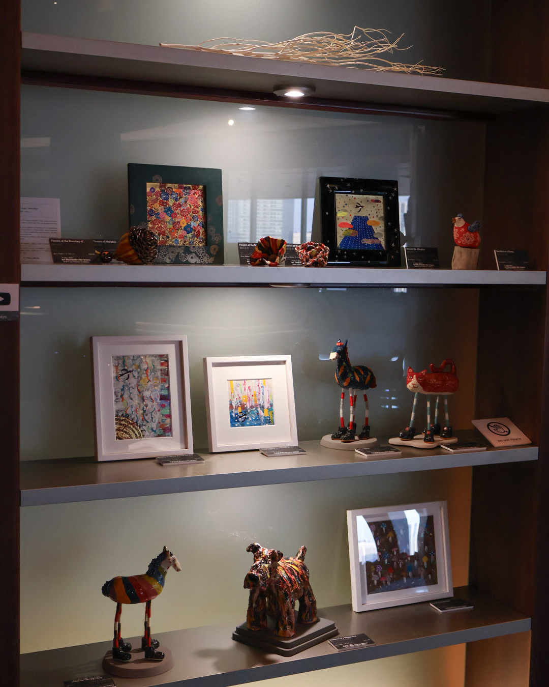 Display shelf with small ceramic sculptures and small paintings