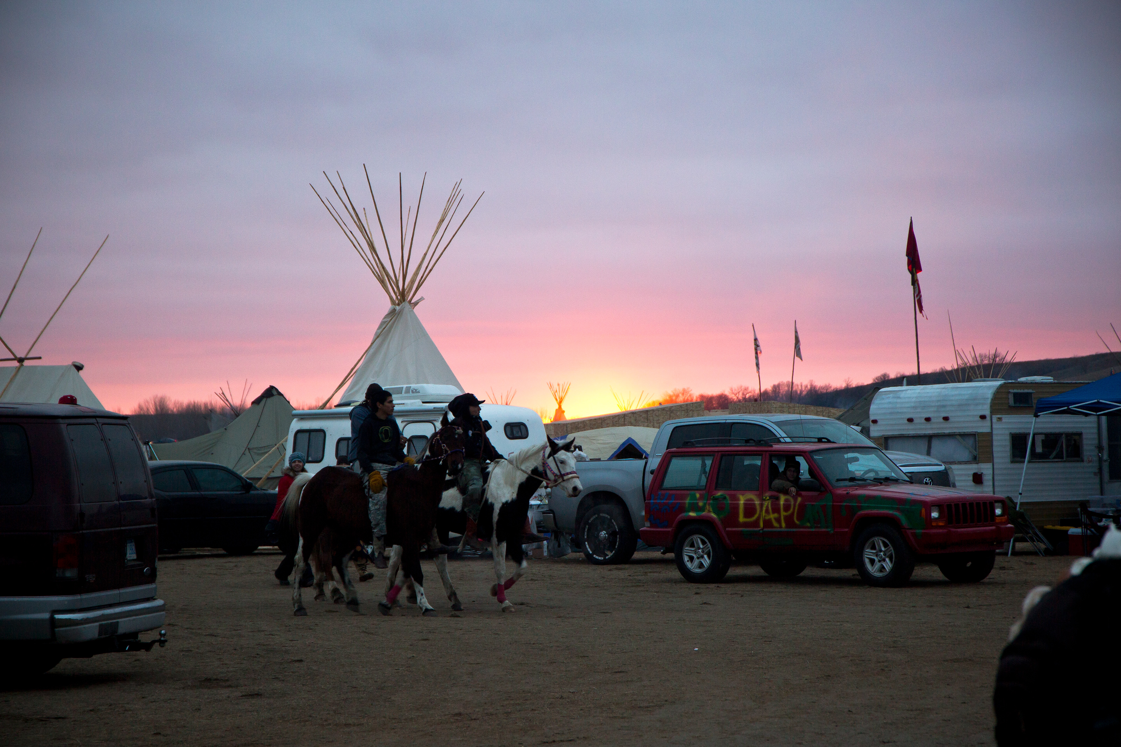 Some indigenous youth ride home at the end of the day through camp.