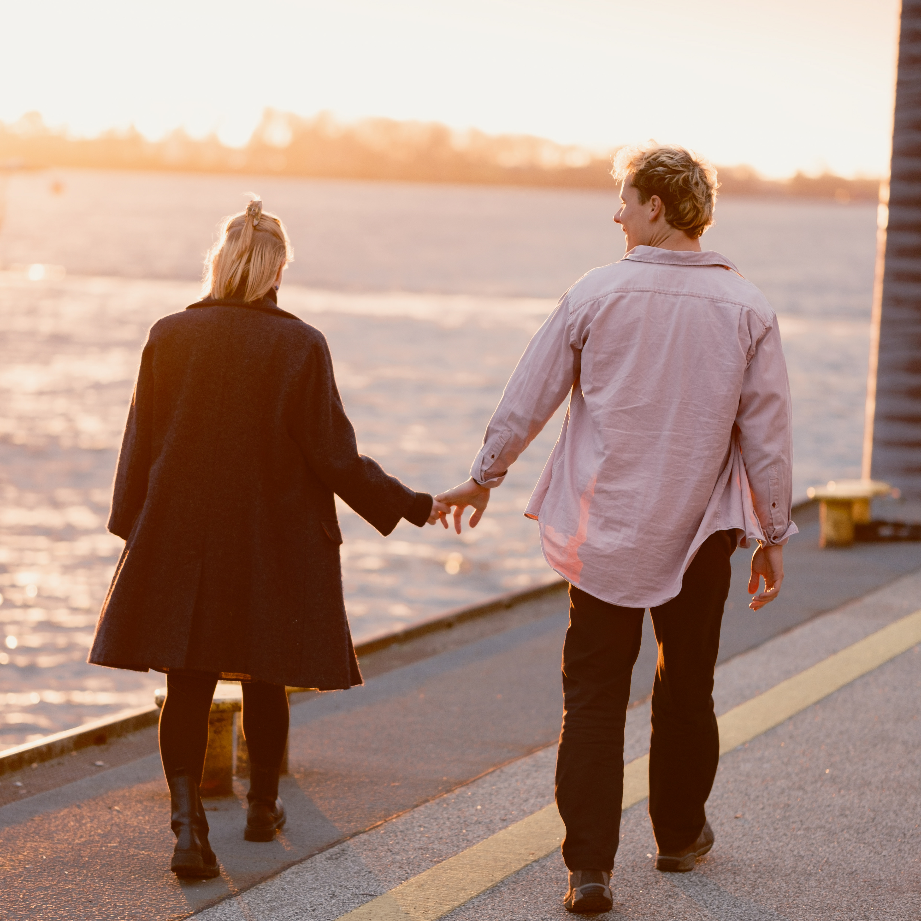 Verliebtes Paar geht am Fähranleger Övelgönne entlang, hält locker Händchen und genießt die untergehende Sonne. Das Bild strahlt Wärme aus. Ein Klick führt zum Tagesablauf, also wie man sich einen Hochzeitstag mit mir vorstellen kann.