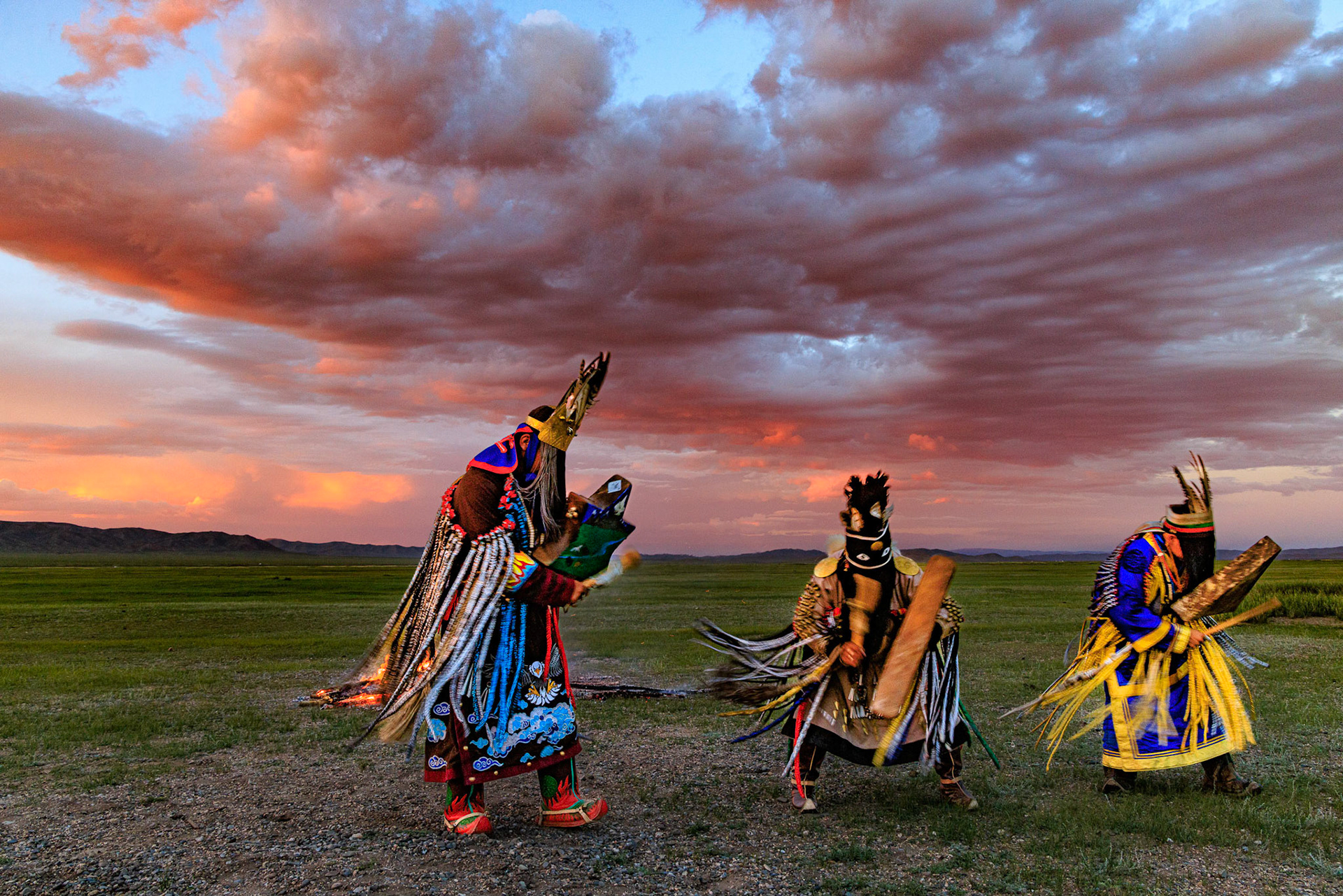 Mongolian Shaman invoking spirits of ancestors at traditional sunset fireside ceremony