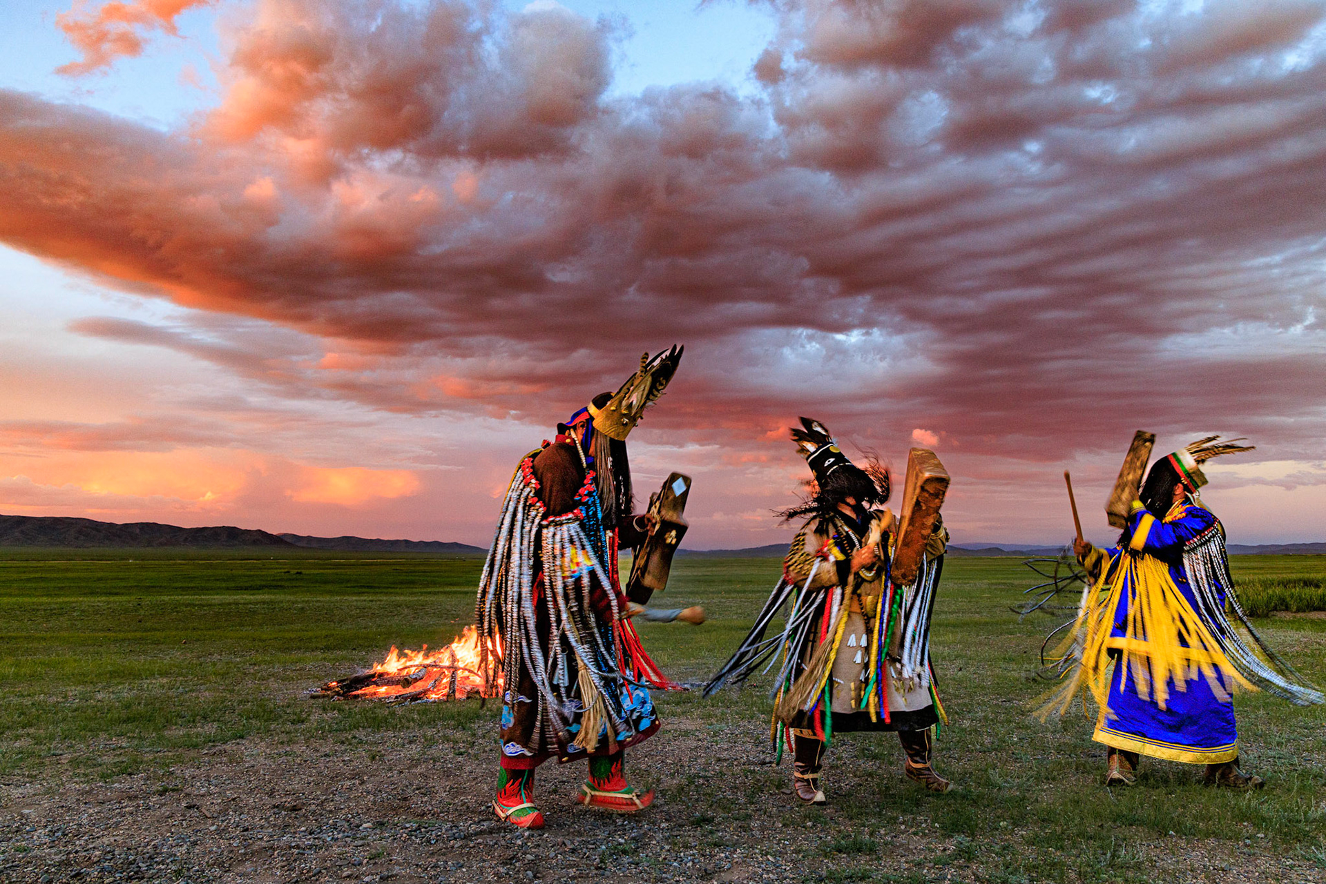 Mongolian Shaman invoking spirits of ancestors at traditional sunset fireside ceremony