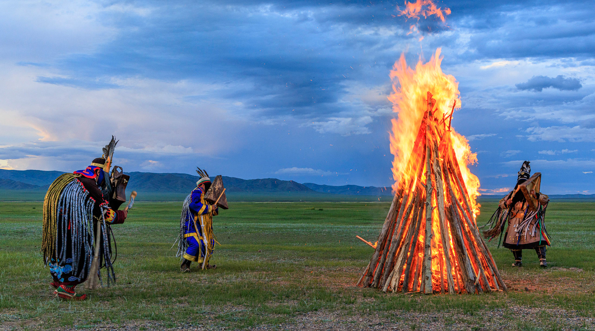 Mongolian Shaman invoking spirits of ancestors at traditional sunset fireside ceremony