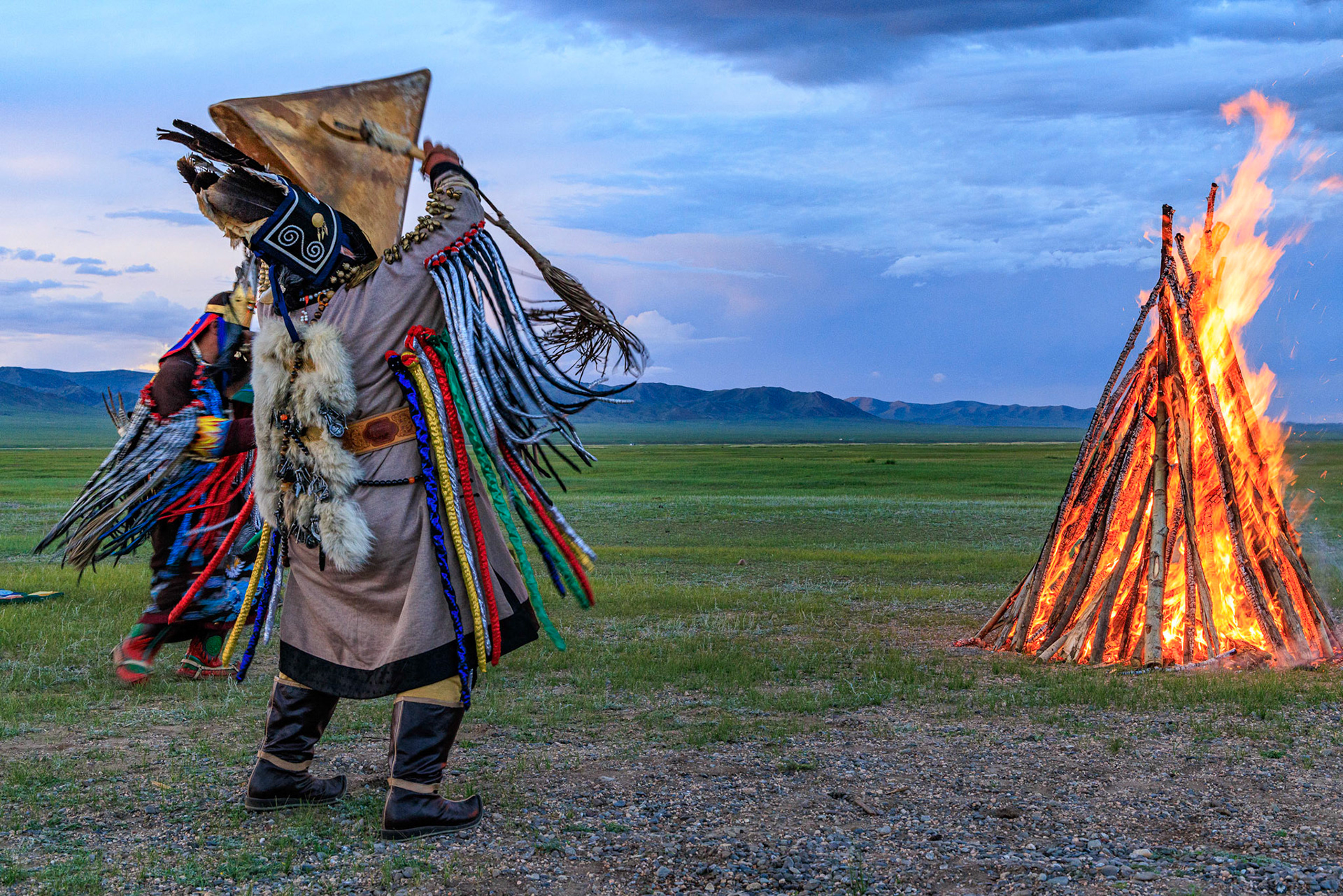 Mongolian Shaman invoking spirits of ancestors at traditional sunset fireside ceremony