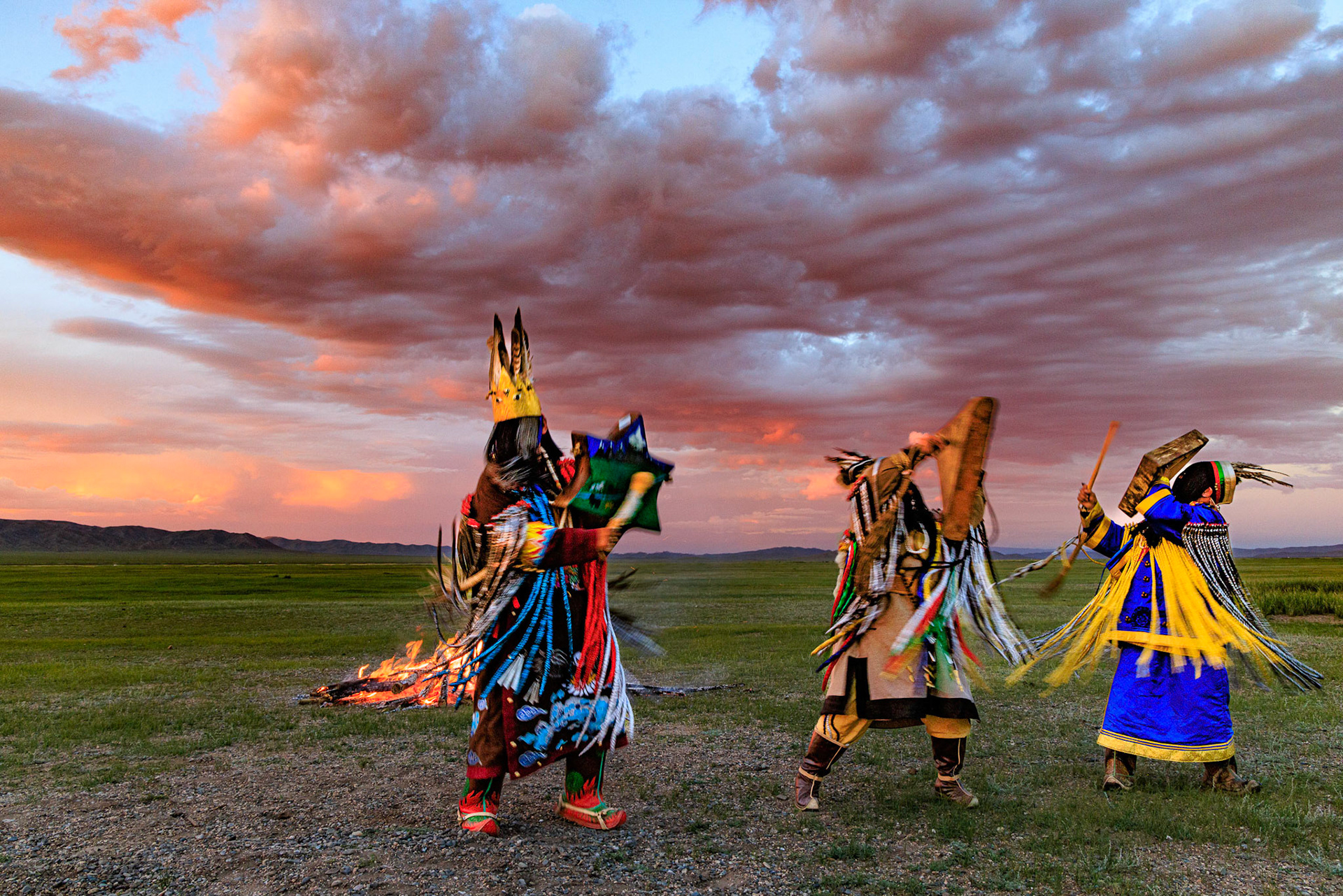 Mongolian Shaman invoking spirits of ancestors at traditional sunset fireside ceremony