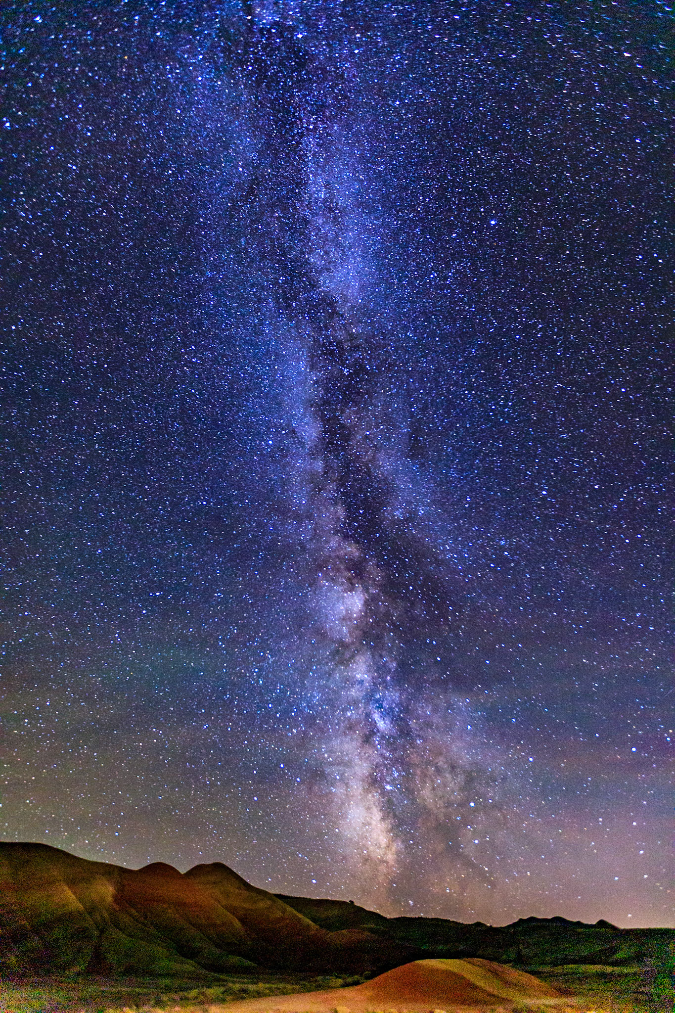 On a early October evening just a few nights past a full moon I had about 40 minutes  after sunset and total darkness before the moon would rise and create too much light to capture the Milky Way over the Painted Hills of John Day National Monument in Oregon. The skies had been very cloudy all day but magically cleared around sunset. I painted the hills with a spotlight on a 30 second exposure at 16mm, f/2.8 and ISO 8000
