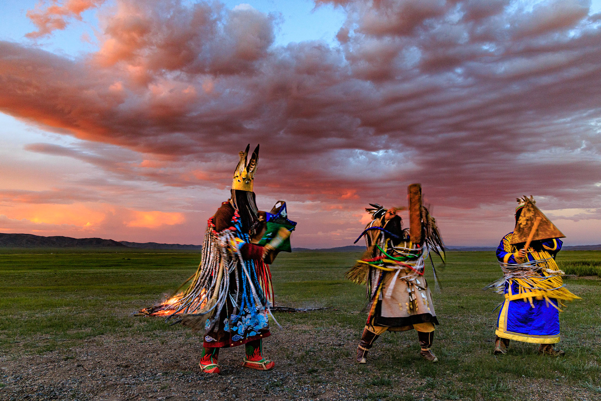 Mongolian Shaman invoking spirits of ancestors at traditional sunset fireside ceremony