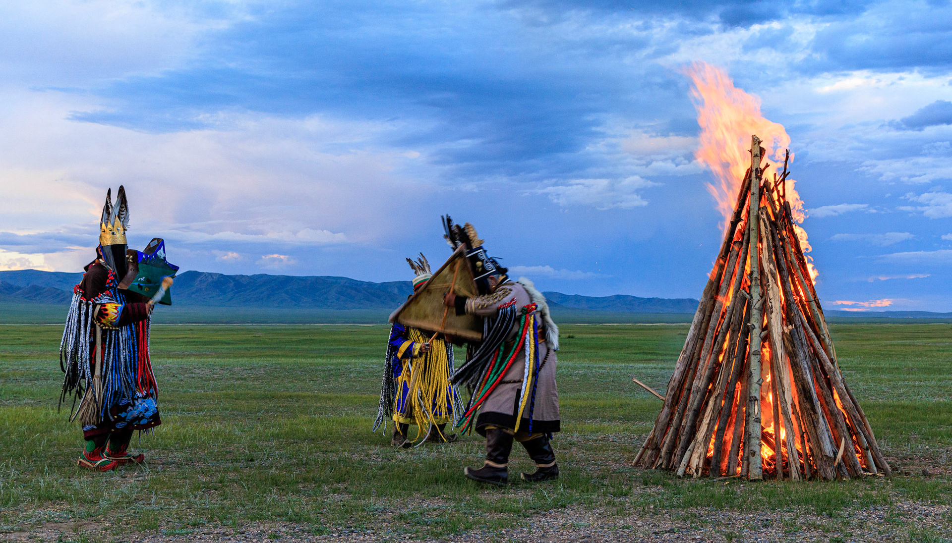 Mongolian Shaman invoking spirits of ancestors at traditional sunset fireside ceremony
