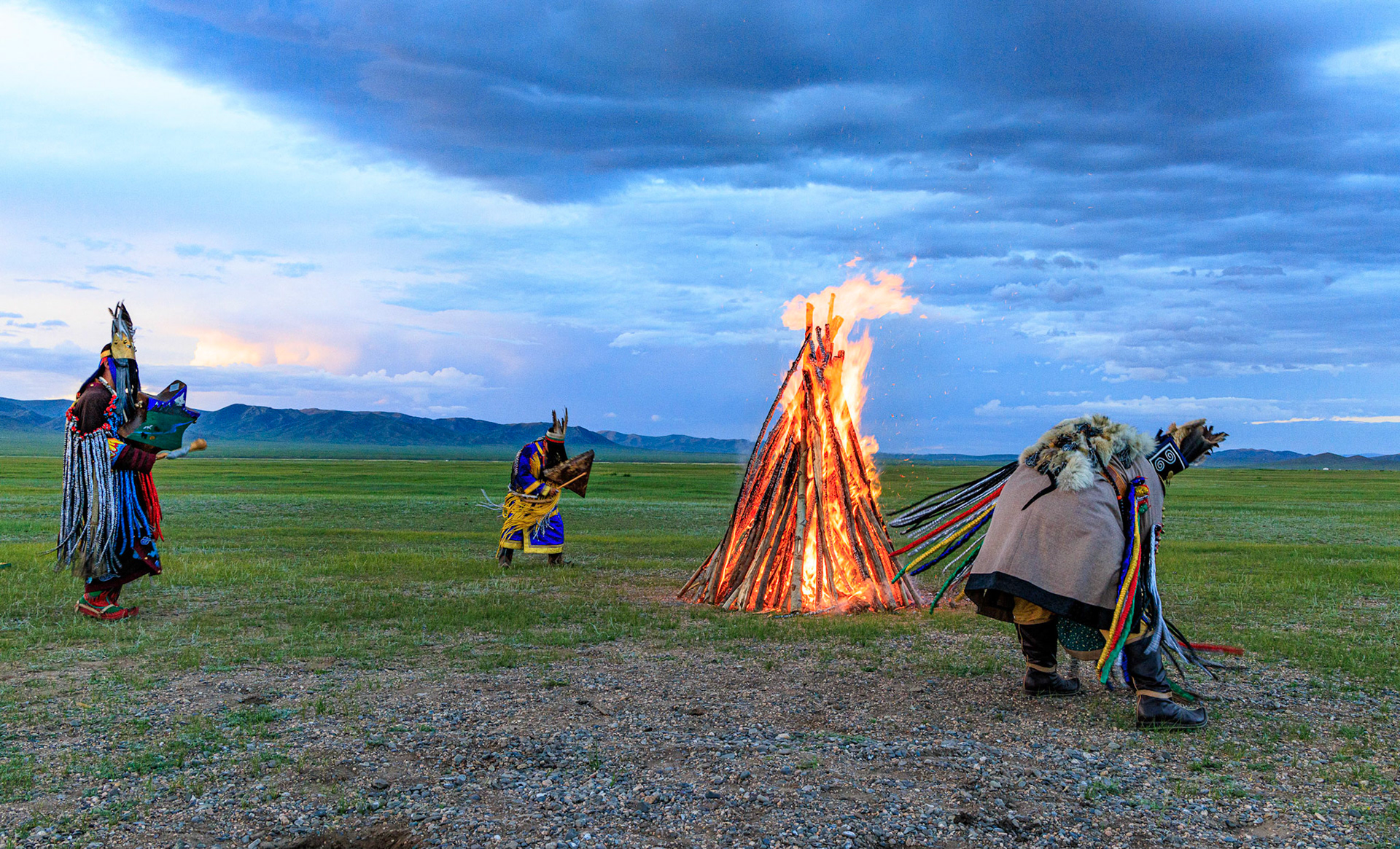 Mongolian Shaman invoking spirits of ancestors at traditional sunset fireside ceremony