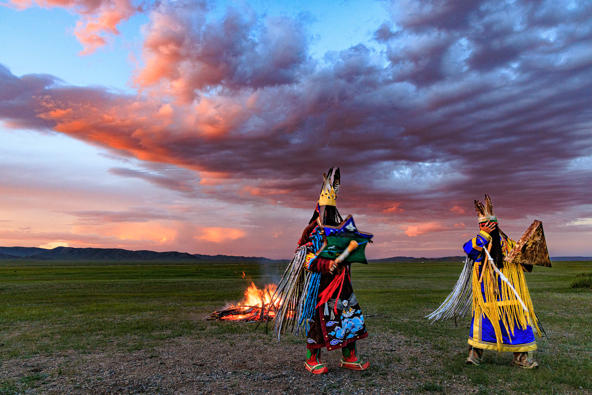 Mongolian Shaman invoking spirits of ancestors at traditional sunset fireside ceremony