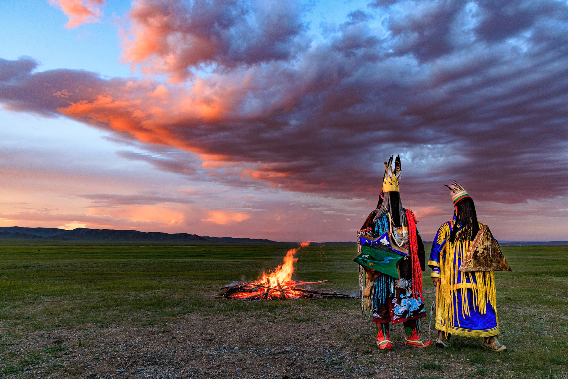 Mongolian Shaman invoking spirits of ancestors at traditional sunset fireside ceremony
