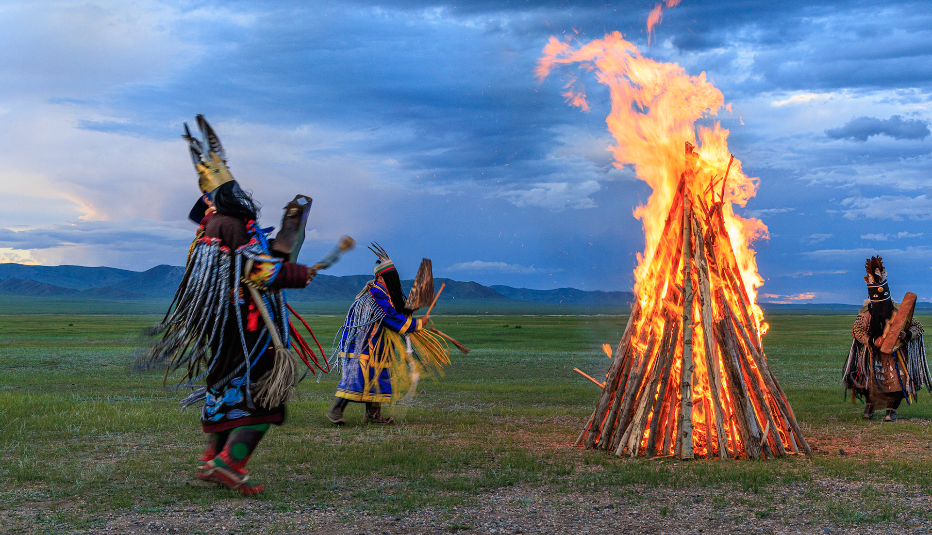Mongolian Shaman invoking spirits of ancestors at traditional sunset fireside ceremony