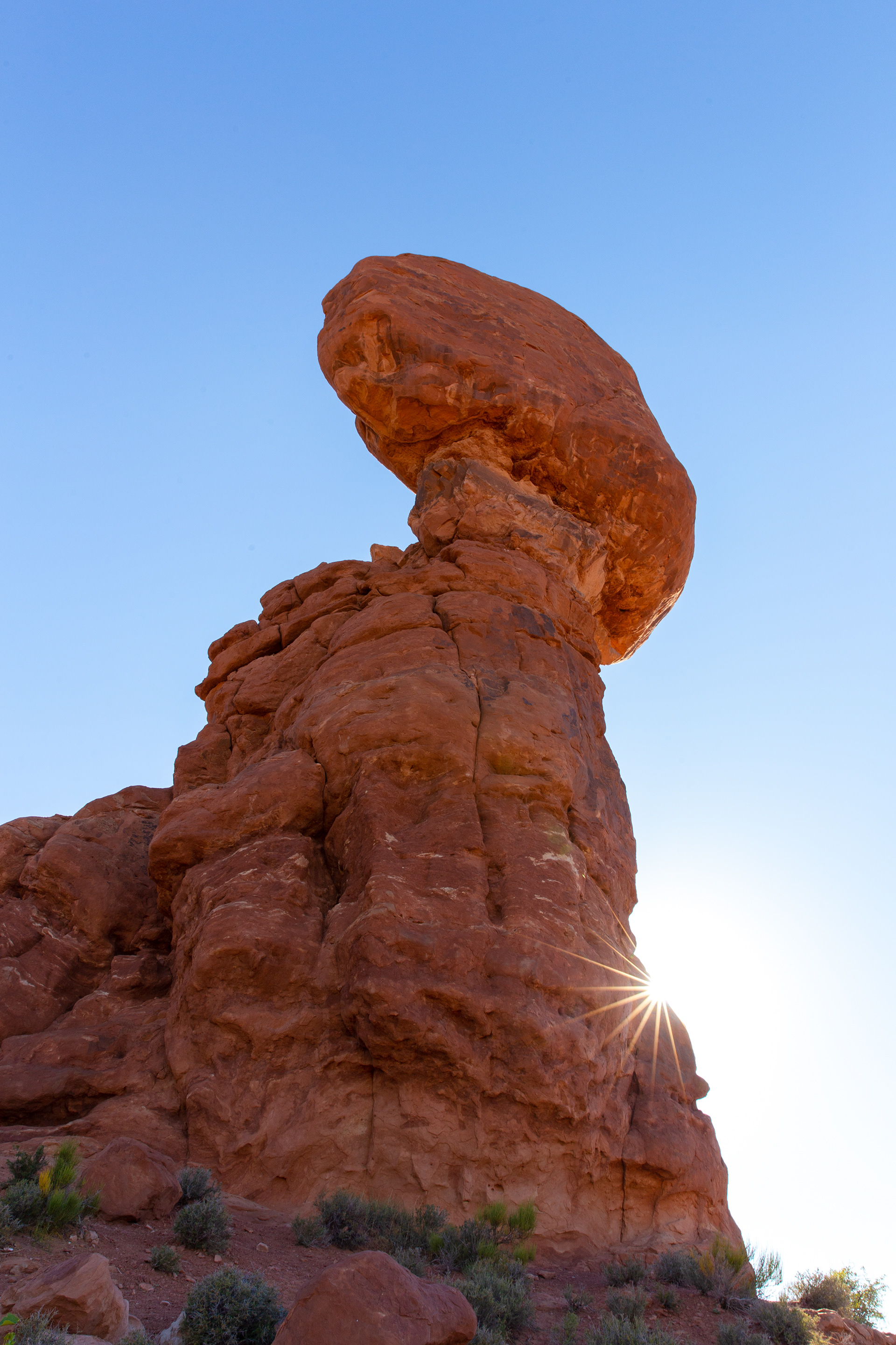 The sun flares out from behind Balanced Rock in Arches NP.