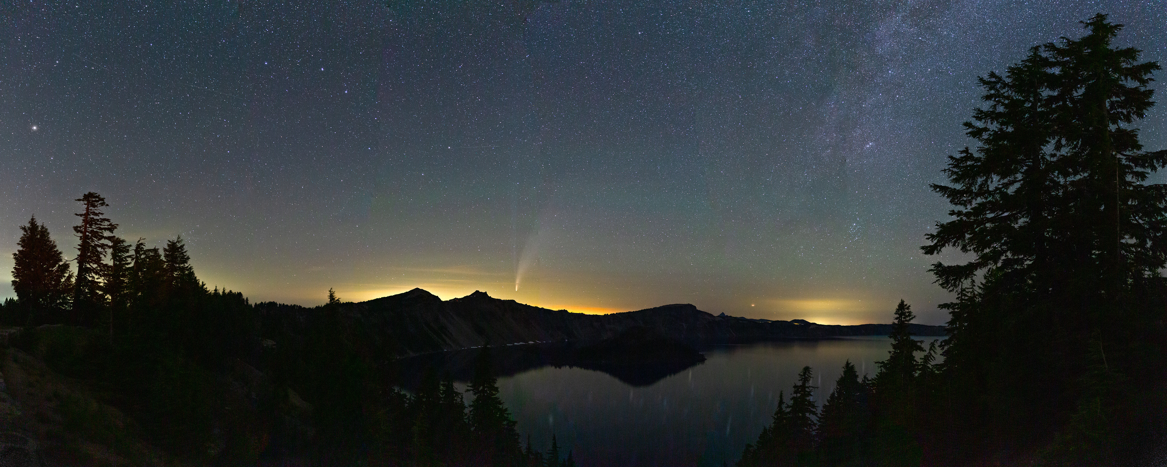 The comet NEOWISE disappears into the glow of Bend, OR in the distance over Crater Lake NP, OR.