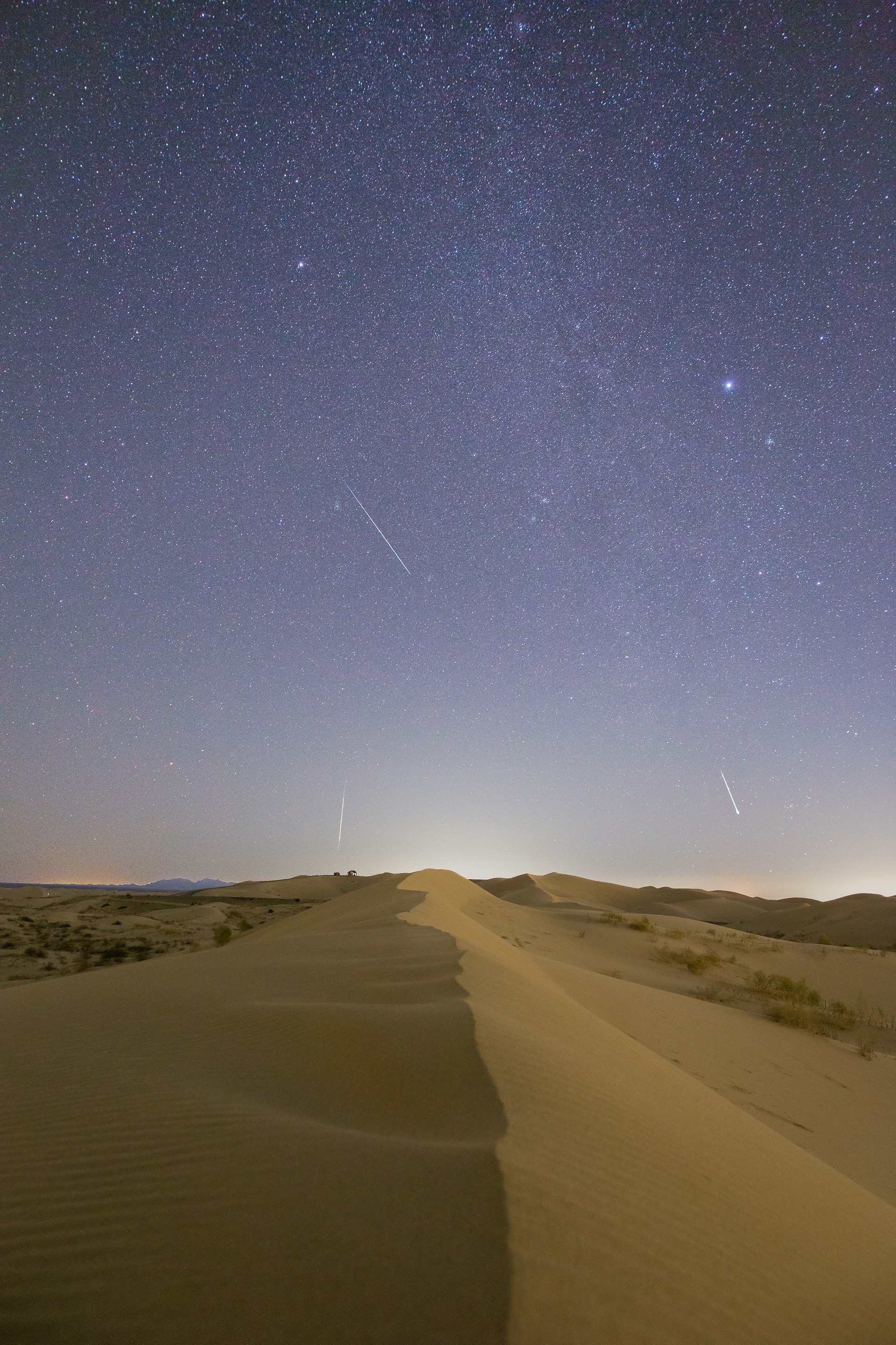 Three meteors streak through the sky during the 2021 Geminids shower over the Algodones dunes.