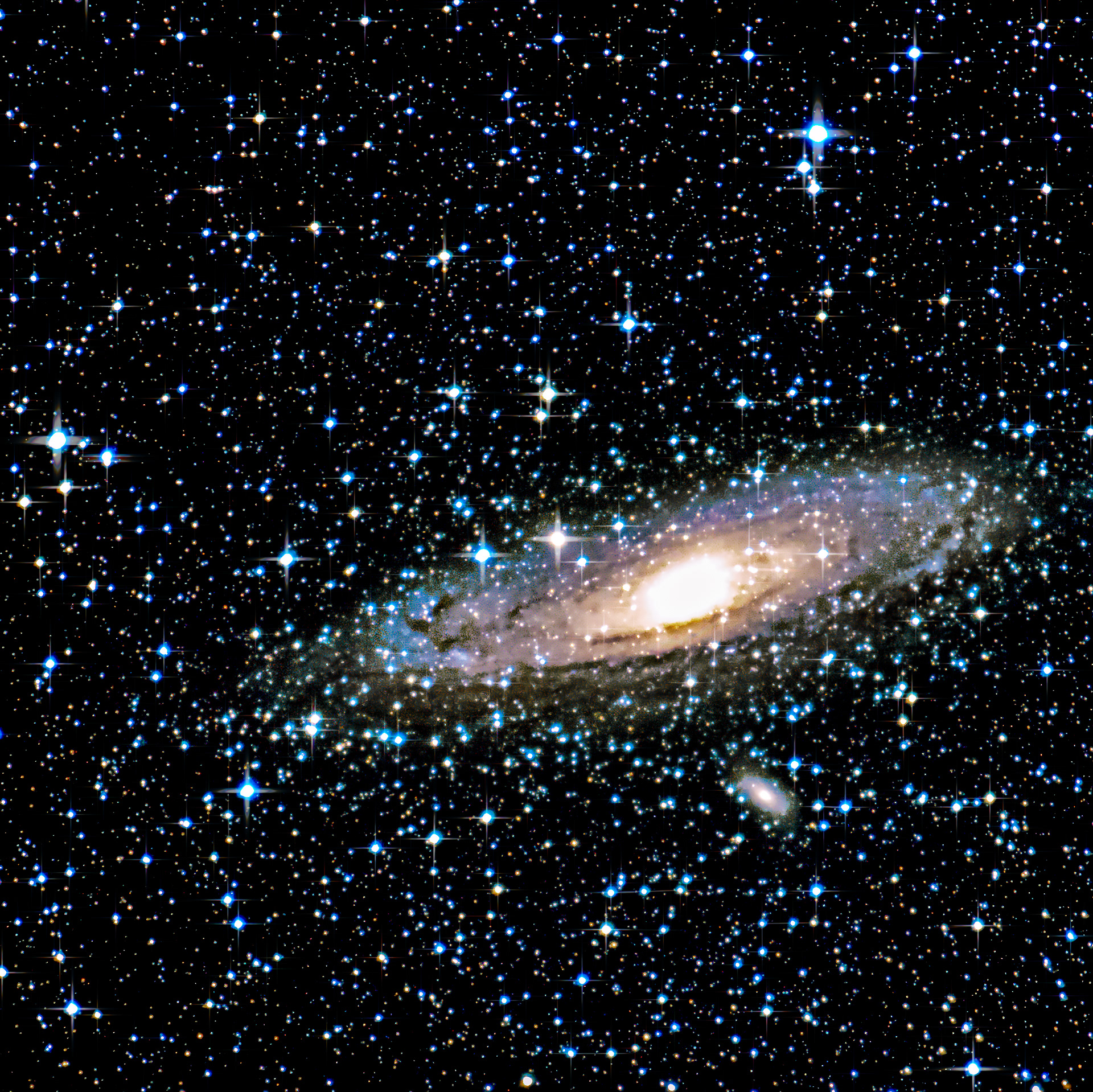 The Andromeda Galaxy shows off its incredible colors with our own stars in the foreground, and another galaxy behind it.