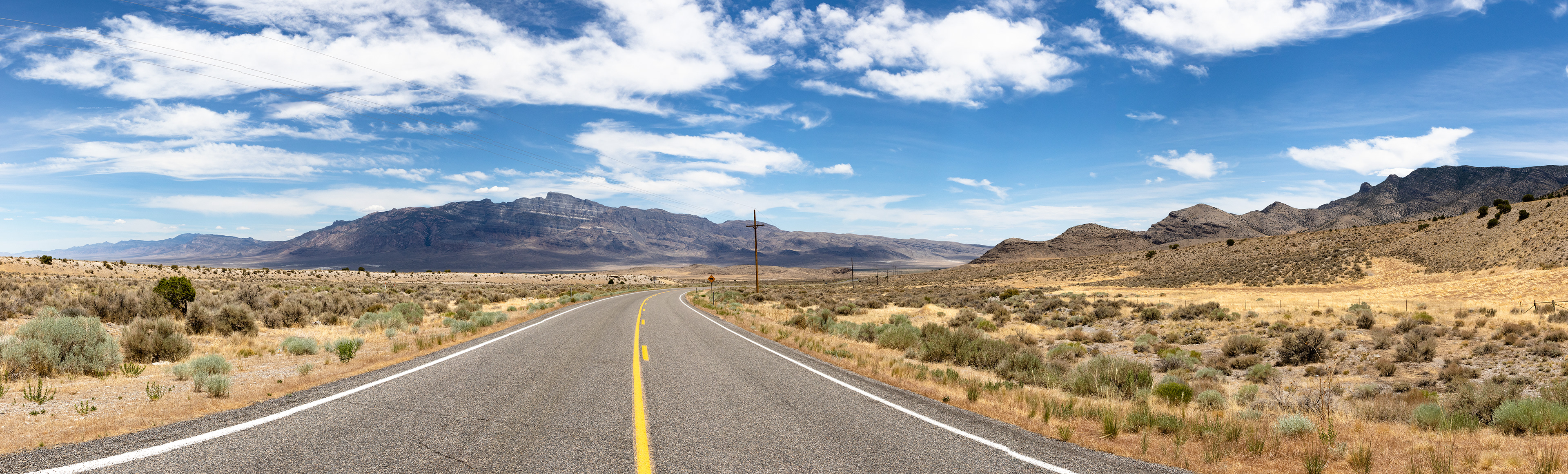 An Eastern Nevada road opens up into a barren landscape.