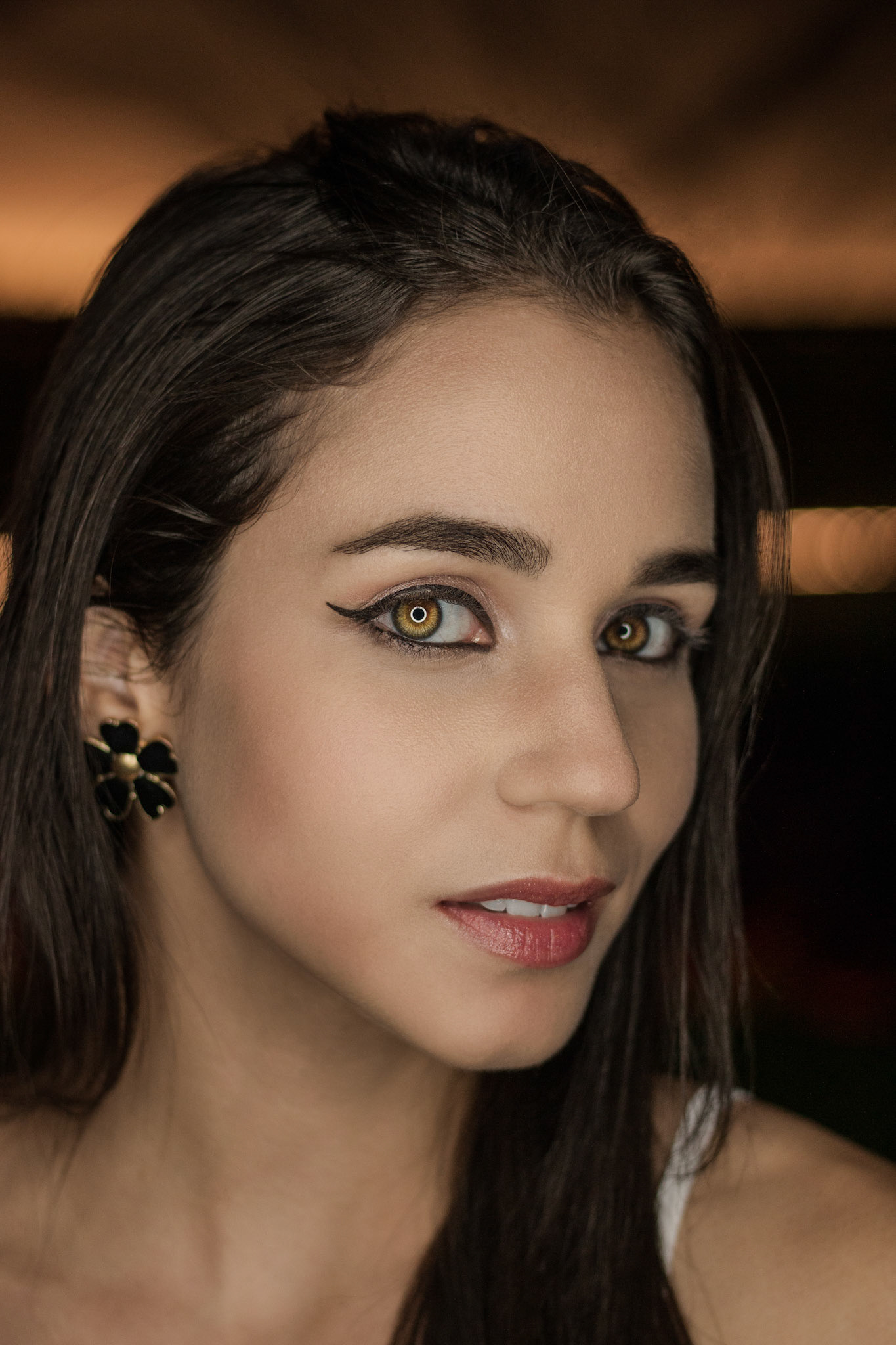 Beautiful young woman looking closely through the lens with ring light effect.