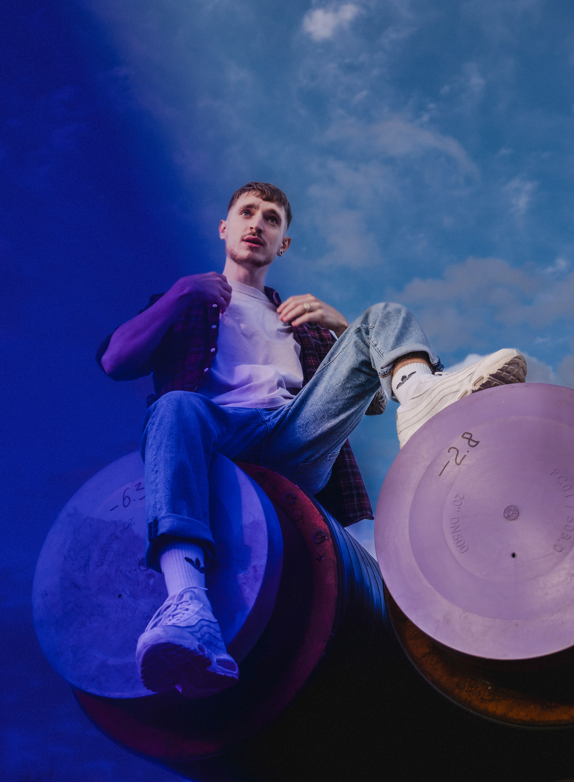 Photography of rapper Dewitt sitting up high against the sky