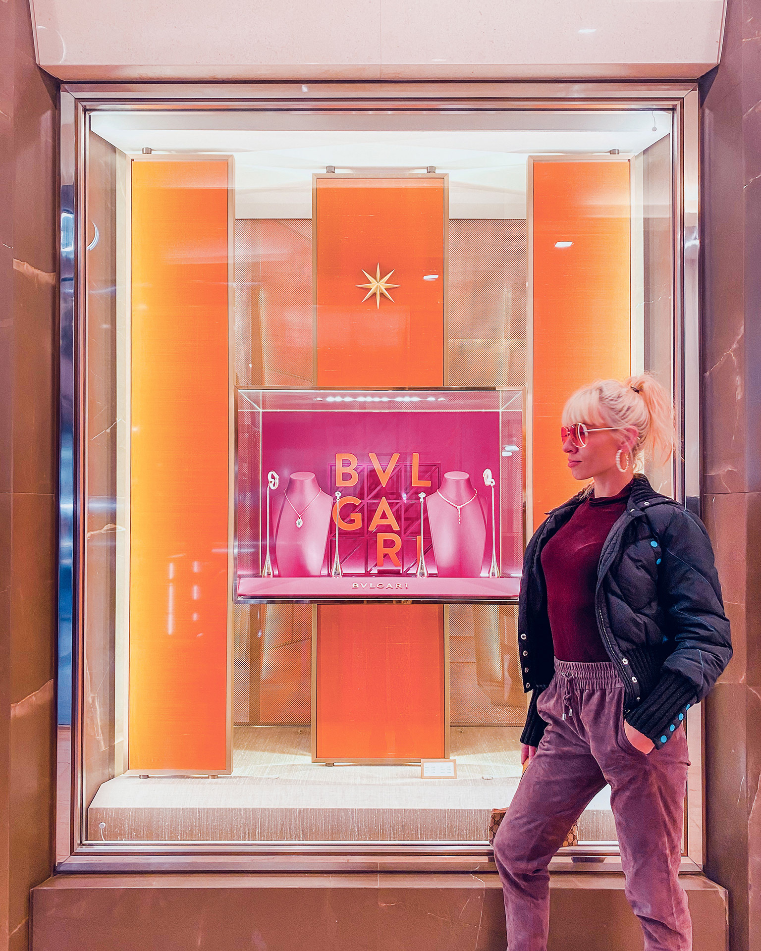 Influencer with pink sunglasses posing in front of a Bulgari shop