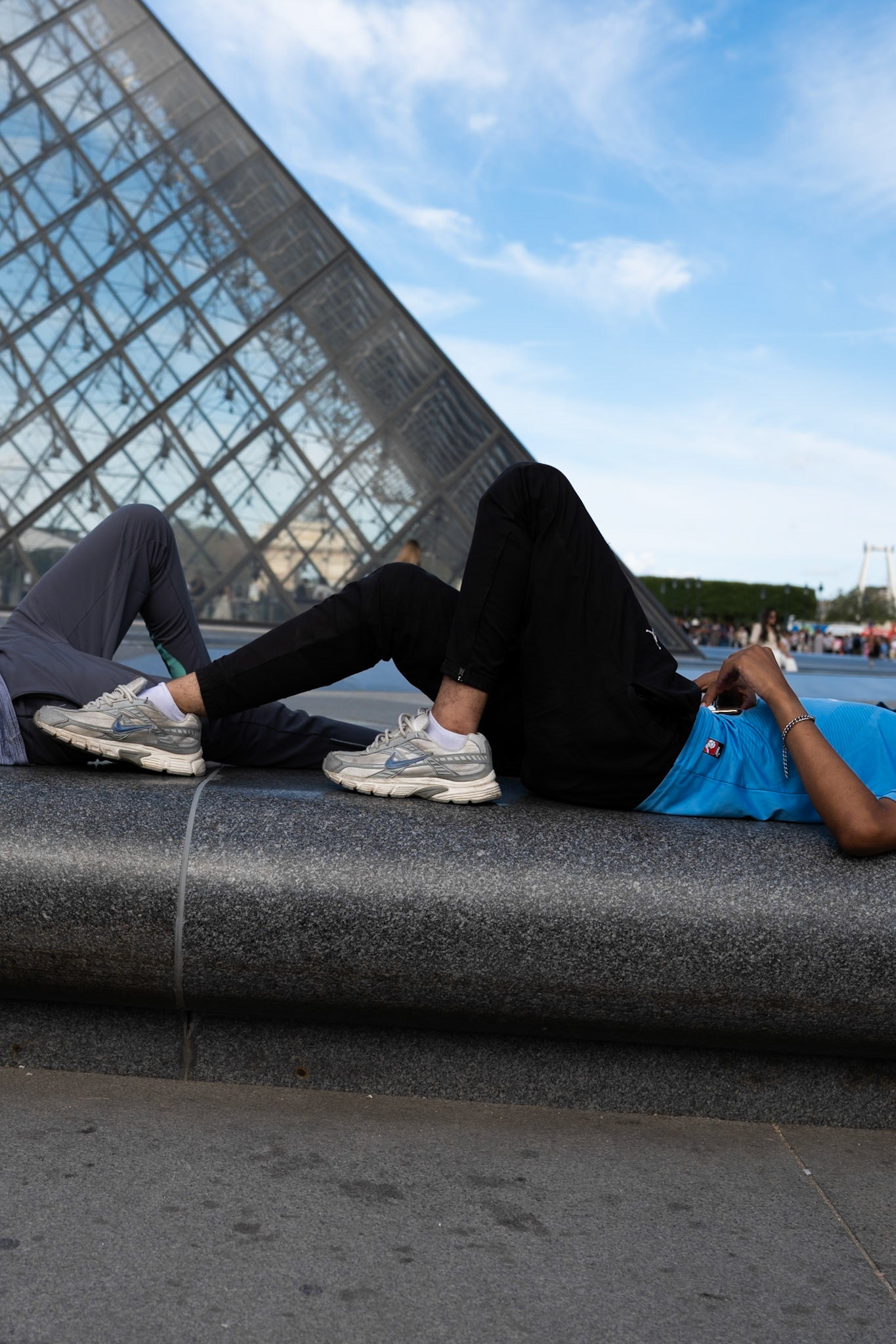 Un homme est allongé devant la pyramide du Louvres