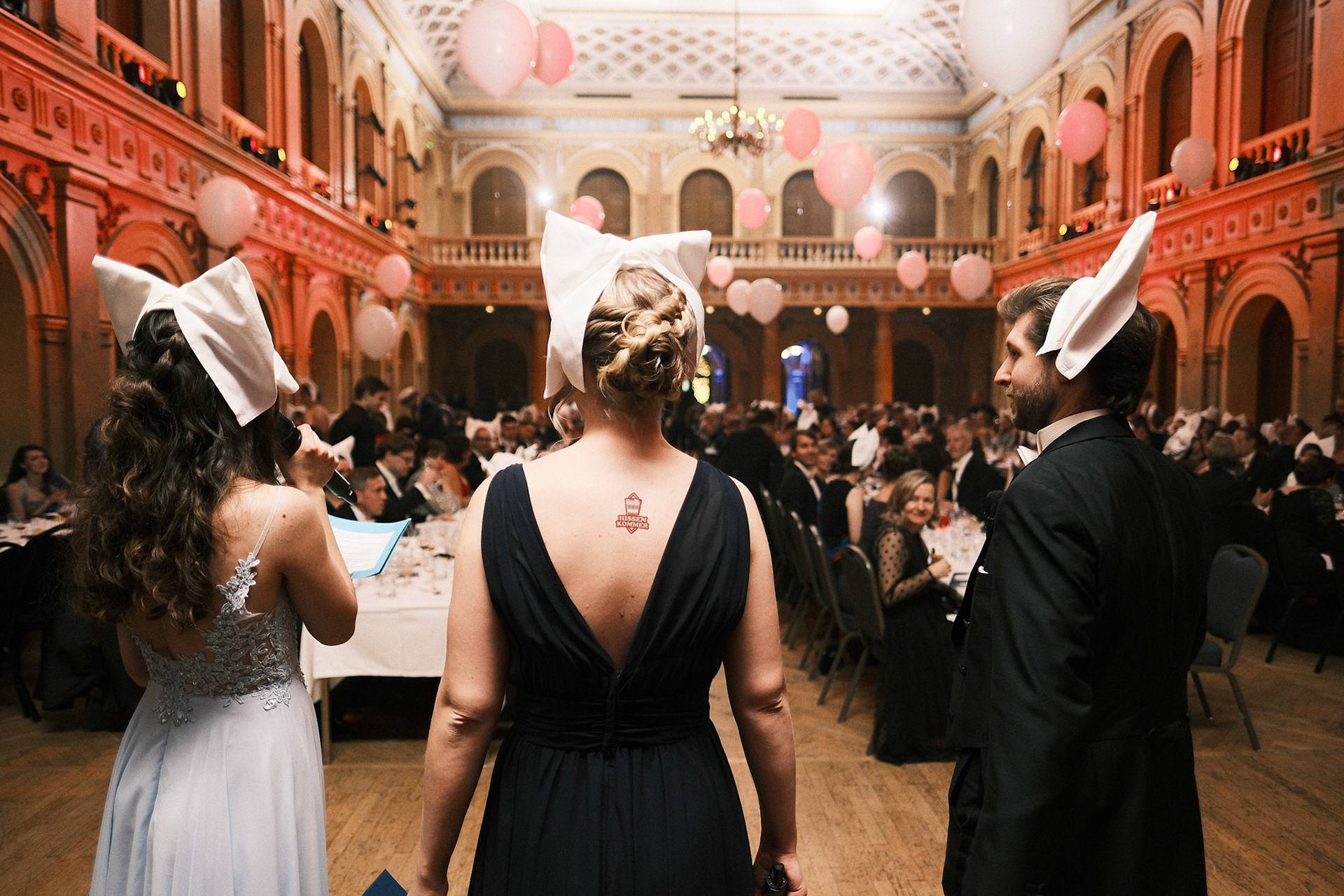 HYY:n 154. vuosijuhla Vanhan ylioppilastalon juhlasalissa. Juontajat ovat pukeneet päihinsä punssikorvat, eli lautasliinoista taitellut päähineet. 2022.