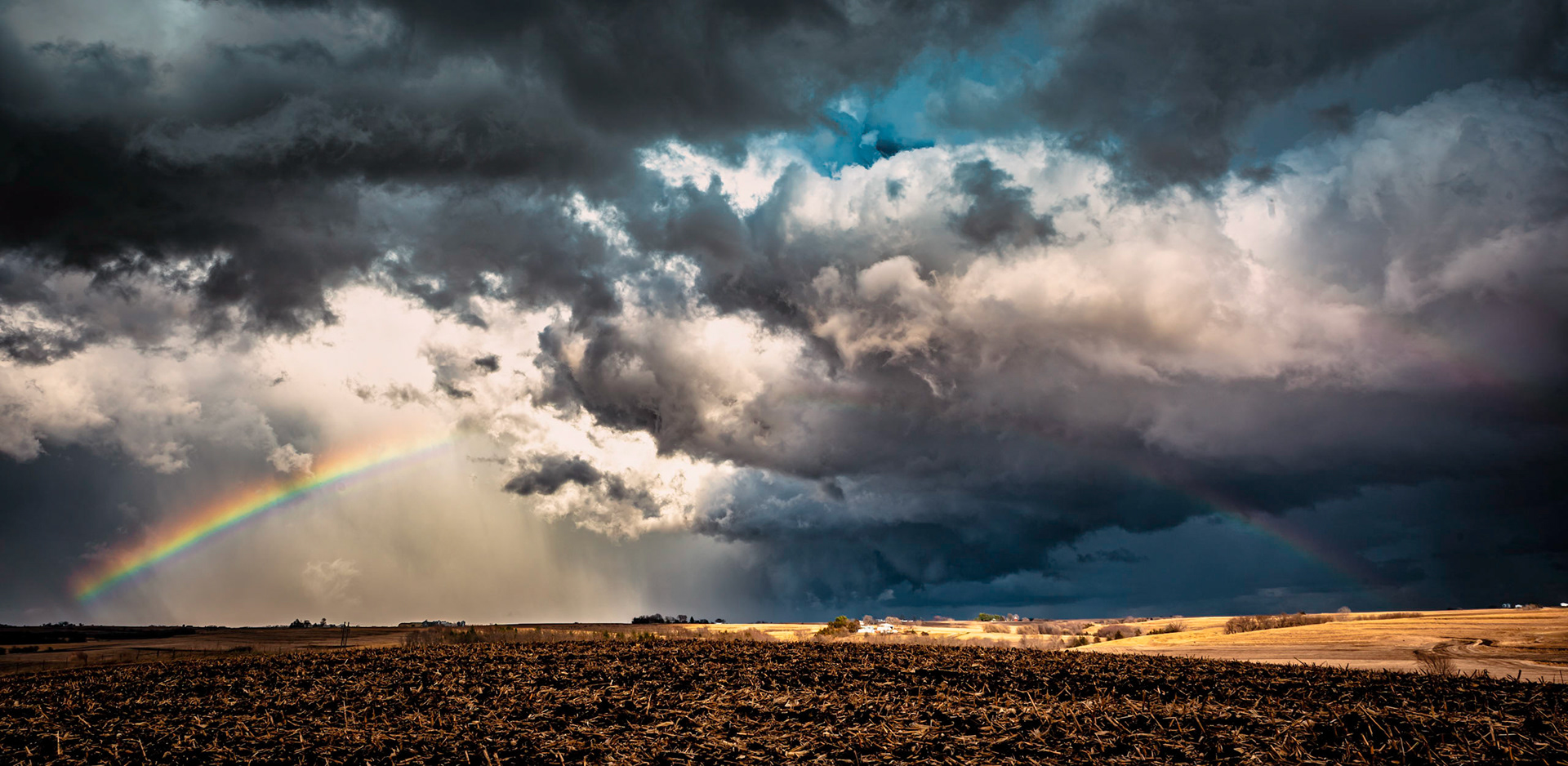 A rainbow appears behind a line of storms.