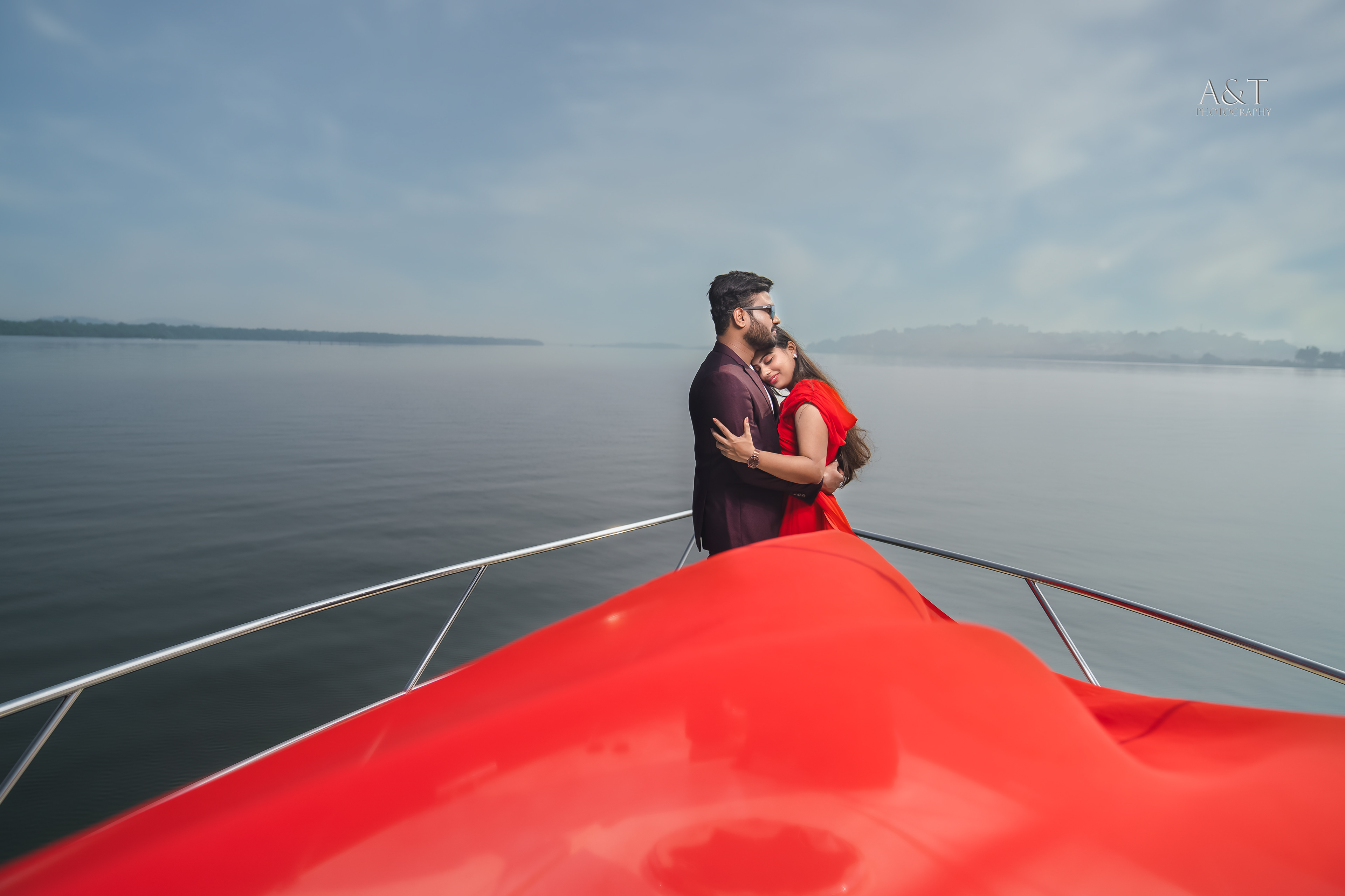 A couple in love, sharing a tender moment against the picturesque ocean backdrop on a luxury yacht in Goa| Photographed by A&T Photography who are best wedding photographer in Goa