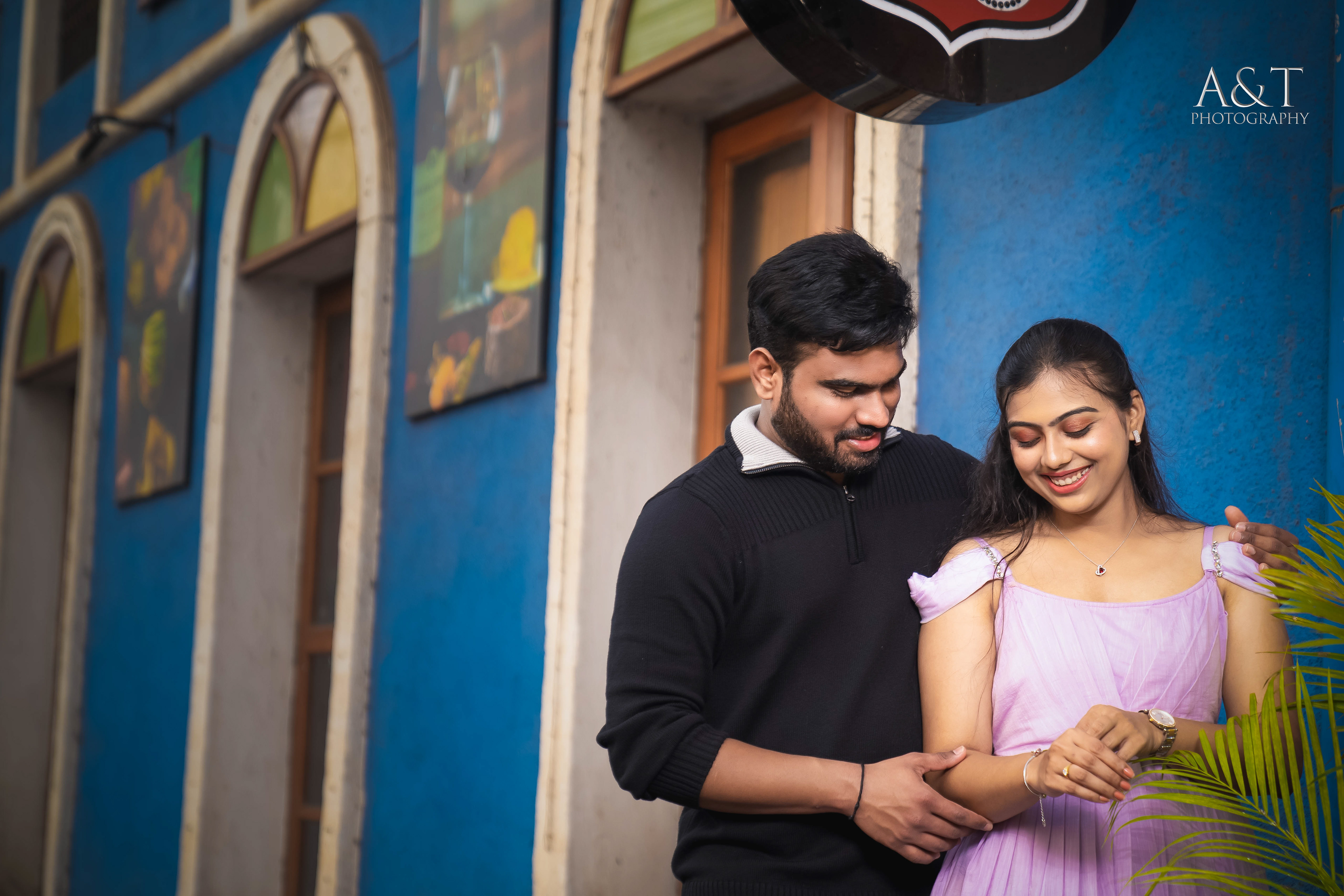The architectural marvel and the couple's affectionate embrace create a timeless pre-wedding moment