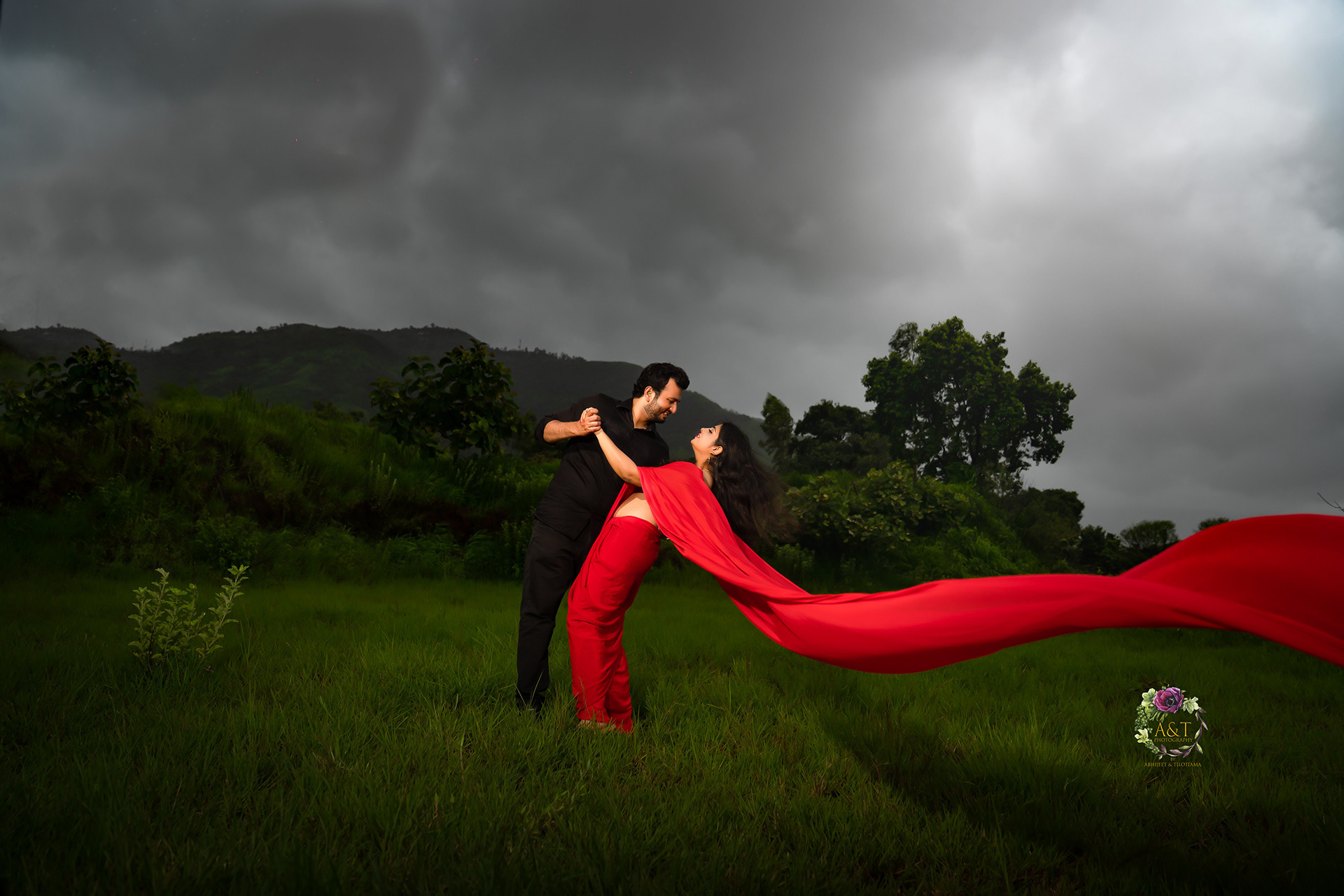 A breathtaking view of a lush green mountain in the background as the couple shares an intimate moment during their monsoon pre-wedding shoot captured by A&T Photography| Best Wedding Photographer in Pune
