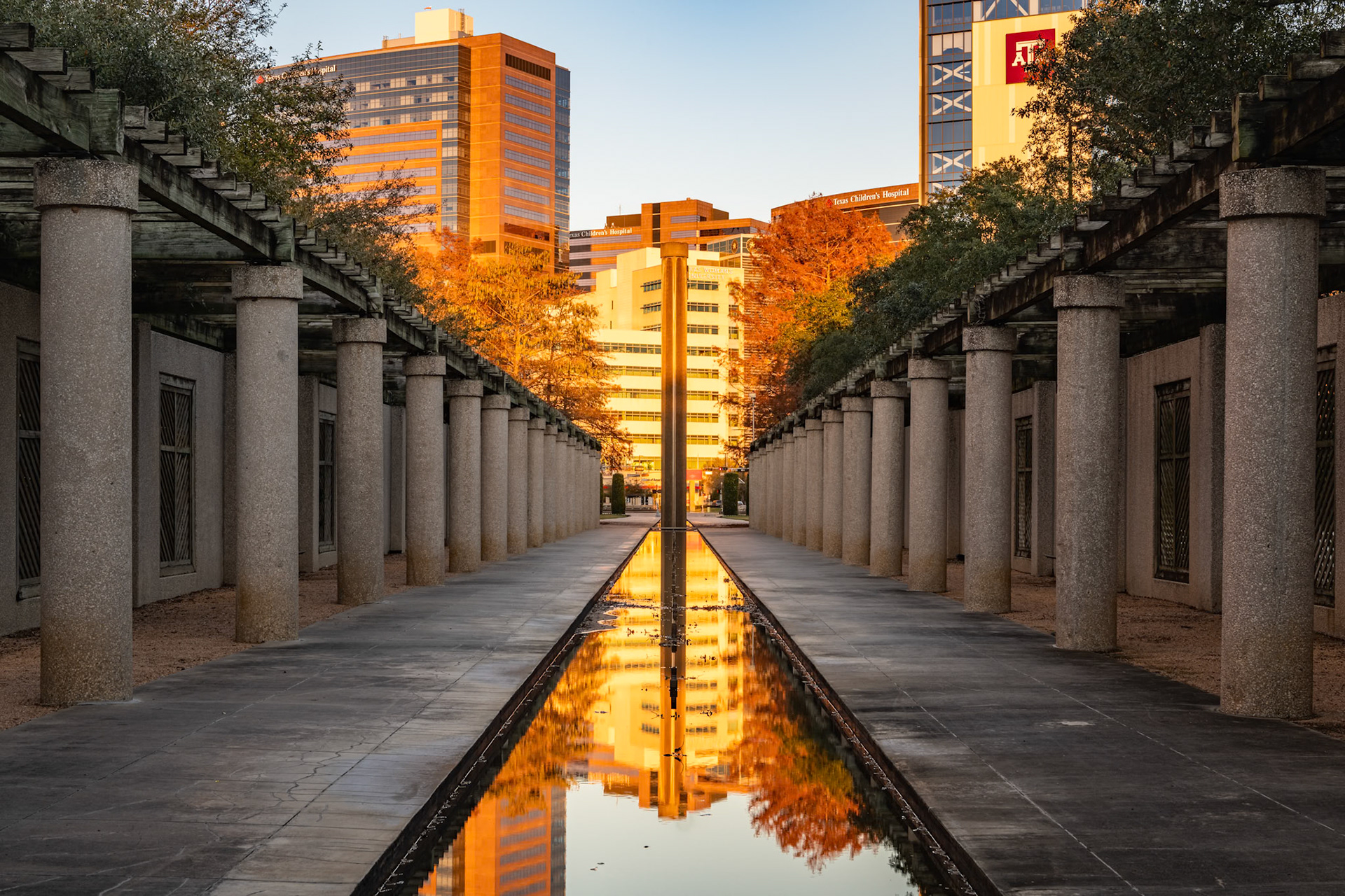 I've seen Gus and Lyndall Wortham Park more than a few times since it sits at the corner of Main Street and Holcombe Boulevard, not too far from home. It's part of the Texas A&amp;M Health Science Center campus in the Texas Medical Center. For whatever reason, I had not thought to photograph it.I was playing around with PhotoPills and realized that the sun would set more or less along the axis of the fountain pool this day. When I arrived, I could see that the fountains weren't running, but the pool was still full. Consequently, it created a reflecting pool. I lined up the camera with the row of columns that sit in the northeastern end of the fountain. When the fountain is operating, water cascades over the columns.The buildings in the background are primarily those of Texas Children's Hospital.Date: 3 January 2021Location: Houston, Texas, United StatesOriginal resolution: 45 MPProcessing: Processed from RAW using Adobe Photoshop Lightroom Classic 10