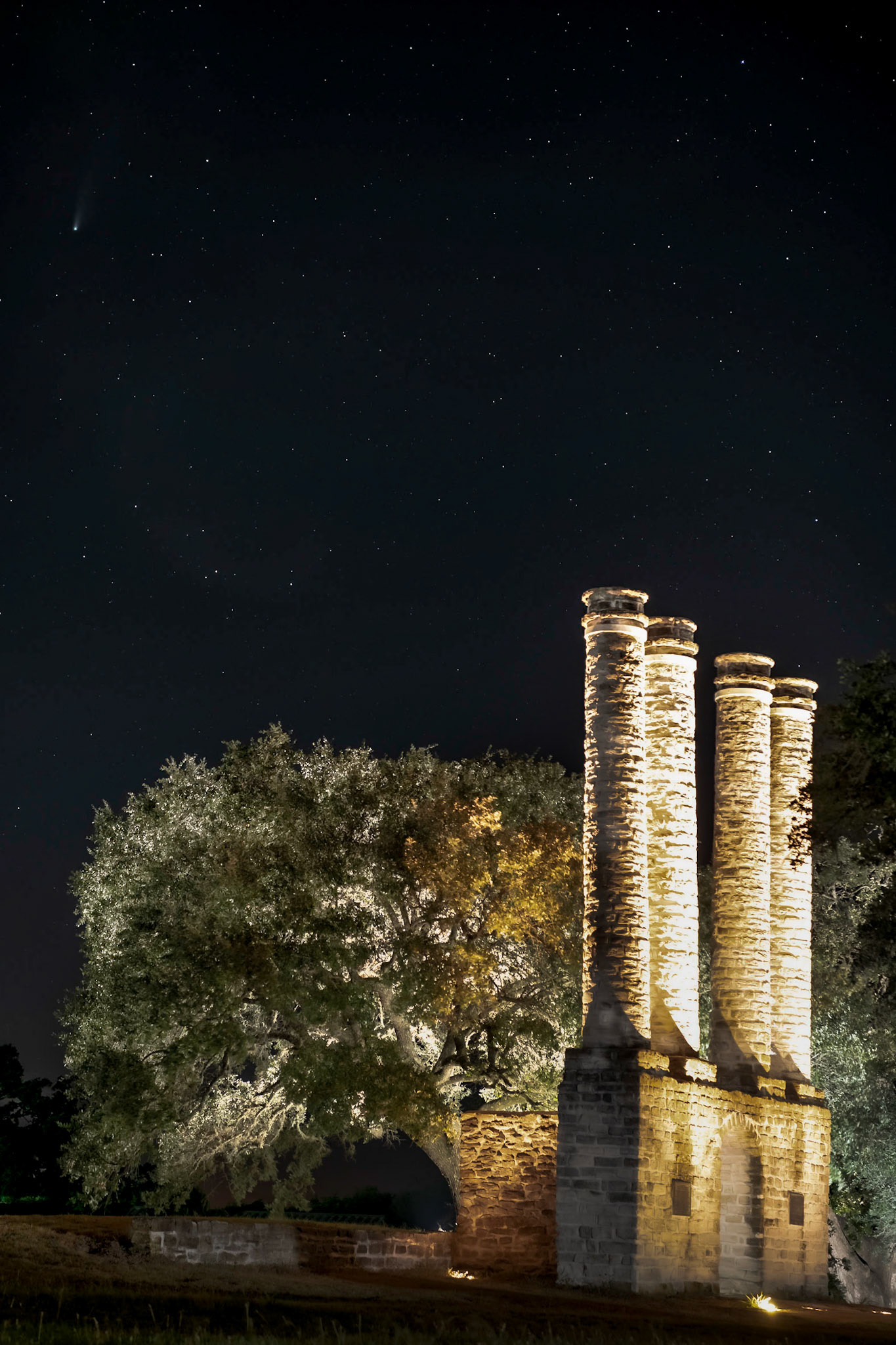 We were in the Independence area to photograph wildlfowers on what was supposed to be an off-and-on rainy afternoon As the day approached sunset, I realized that the skies  might actually clear and that we would get a chance to photograph Comet NEOWISE.I used a 24-70 mm zoom to frame the lit columns at Old Baylor Park. In hindsight, I might have been better off using a longer focal length to magnify the comet, but that would've put me across the highway on private property, so I compromised on this shot. You can see the comet in the upper left. This image was made from ten light frames taken over about a minute using Starry Landscape Stacker.Date: 24 July 2020Location: Independence, Texas, United StatesOriginal resolution: 45 MPProcessing: Processed from RAW using Adobe Photoshop Lightroom Classic 9