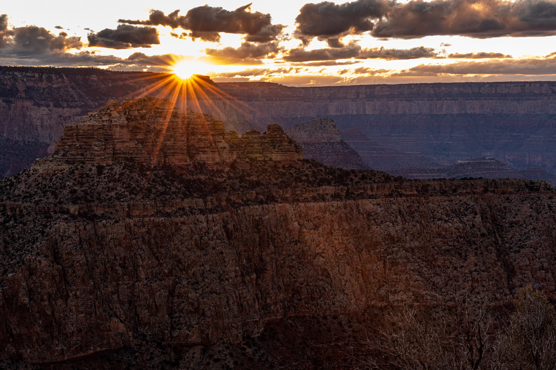 On our second day at the Grand Canyon, our guide took us to Moran Point for sunset. I lined up this shot of the sun setting over Coronado Butte and closed down the aperture to get a sun star effect.  Date: 17 March 2020Location: Grand Canyon National Park, Arizona, United StatesOriginal resolution: 45 MPProcessing: Processed from RAW using Adobe Photoshop Lightroom Classic 9