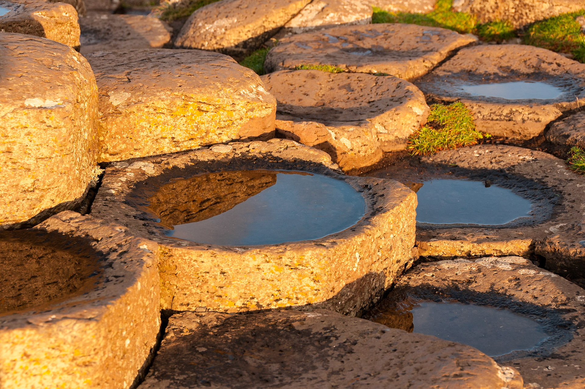The tops of several basalt pillars at the Giant's Causeway were dished because of the uneven contraction of the molten rock as it cooled. After the tide receded, the bowls were left filled with water, which created the looking glass effect in the photo.Date: 9 October 2014Location: County Antrim, Northern Ireland, United KingdomOriginal resolution: 12 MPProcessing: Processed from RAW using Adobe Photoshop Lightroom CC 2015