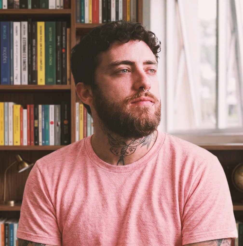 Frederico Tales, autor deste site, com uma estante de livros atrás. Ao lado da estante, uma janela entreaberta.