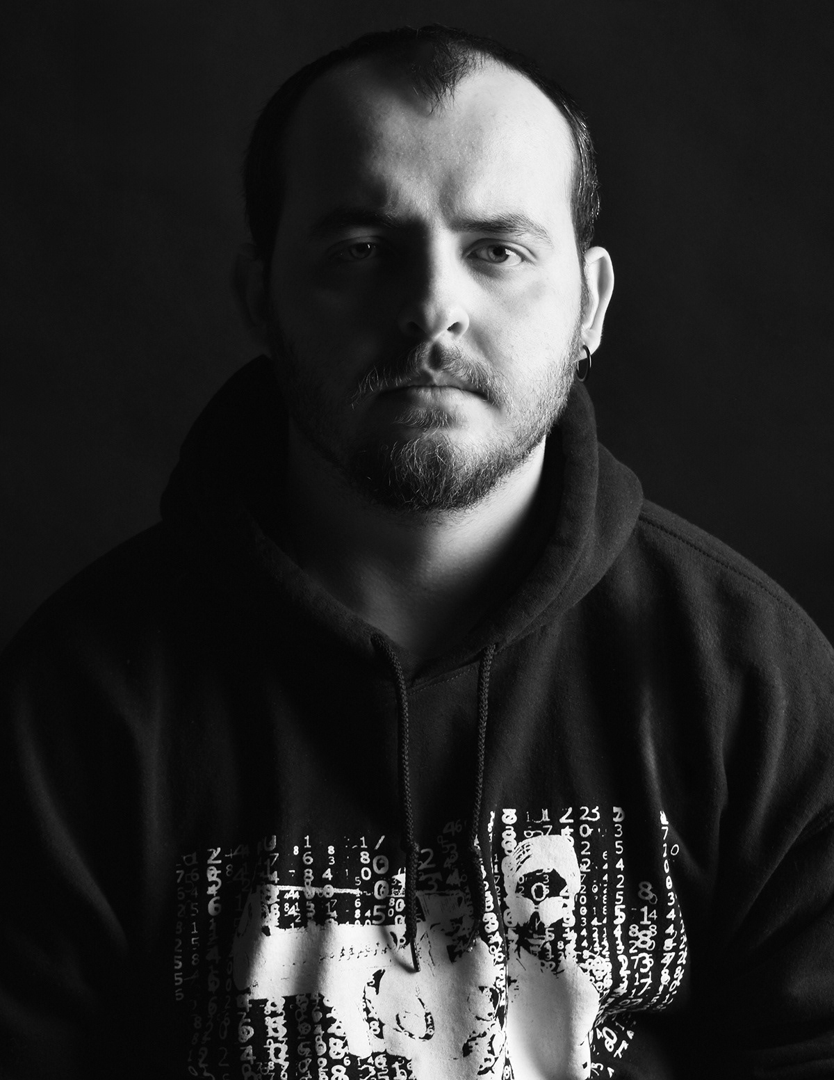 Moody black-and-white portrait with dramatic side lighting and a serious expression.