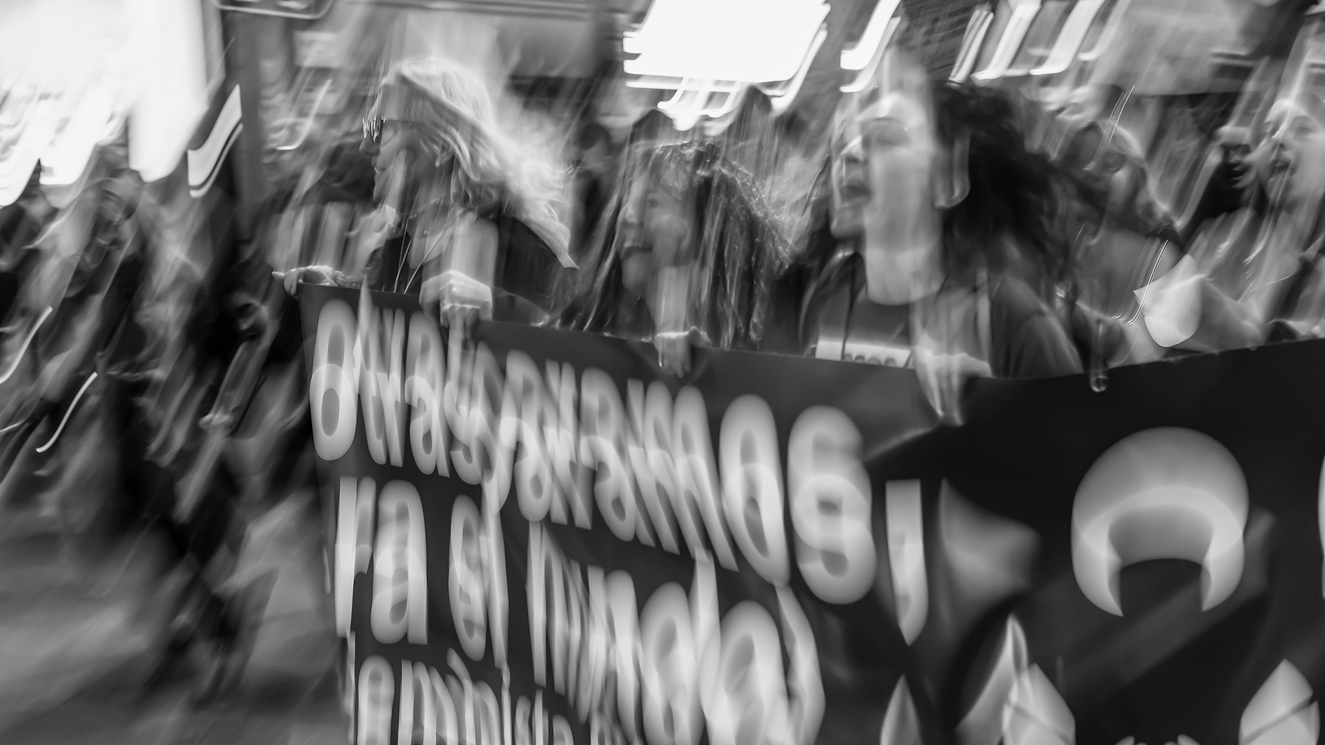 Grite tu nombre escondida tras una pancarta en una multitud.